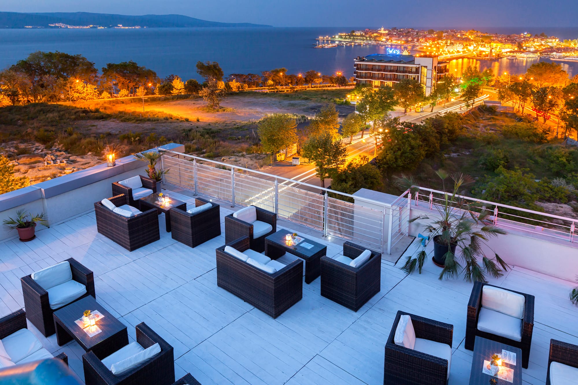 a rooftop patio with chairs and a city in the background