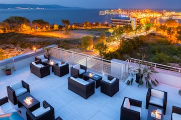 a rooftop patio with chairs and a city in the background