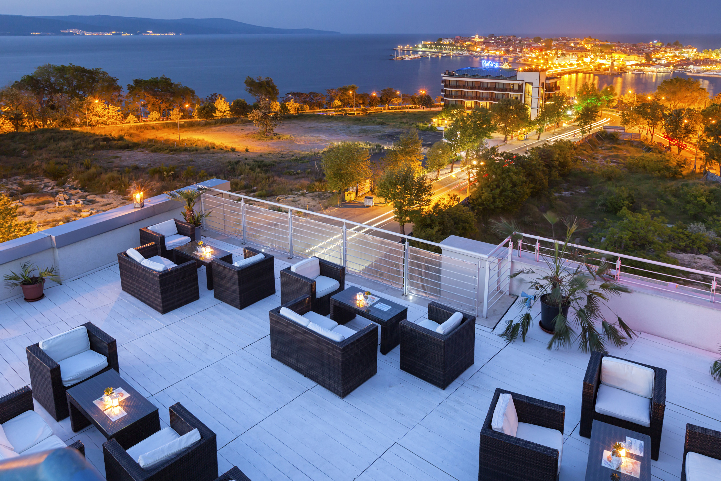 a rooftop patio with chairs and a city in the background