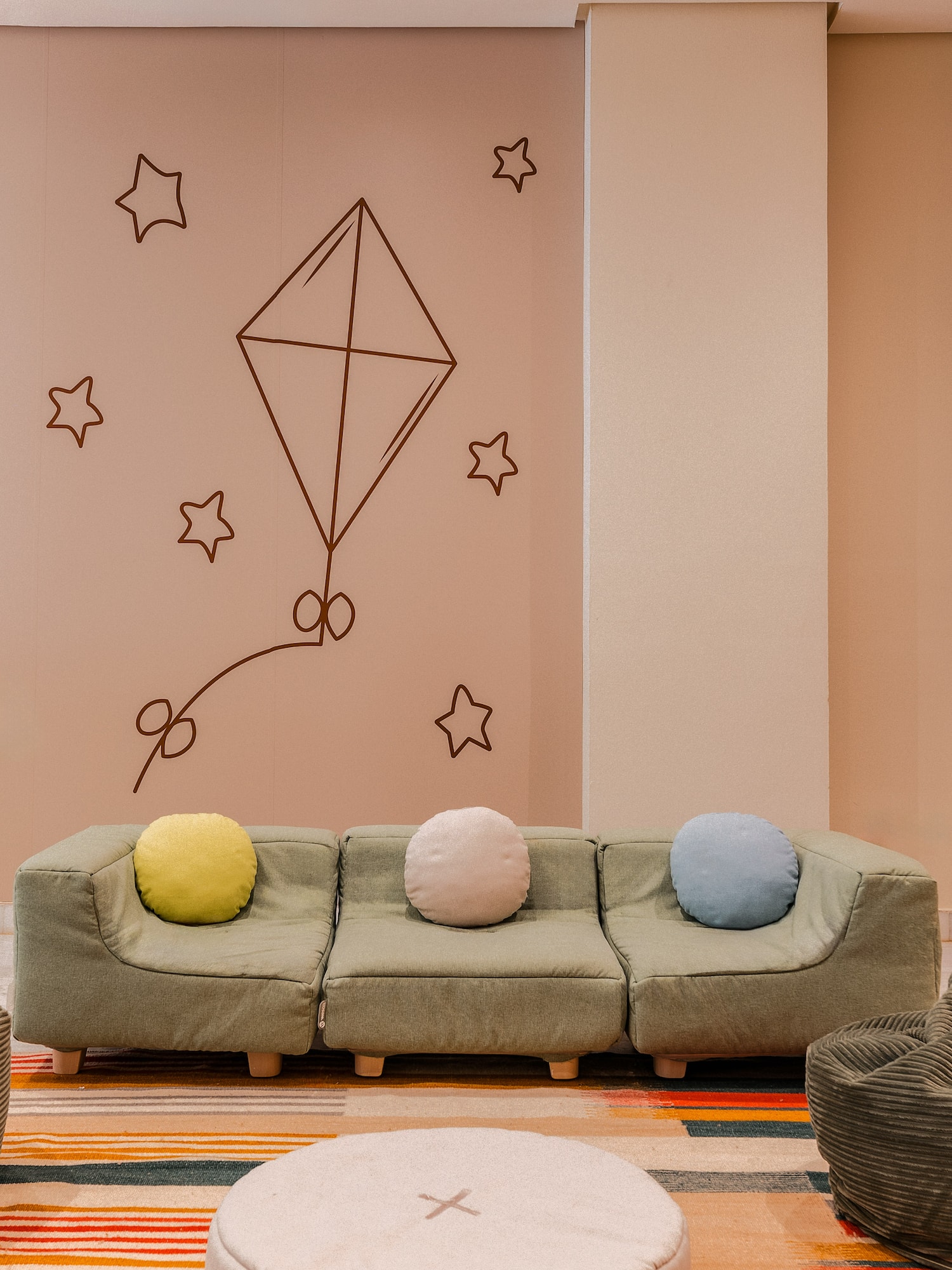 Children's play space: green modular sofa, colorful rug, kite, and star wall art.