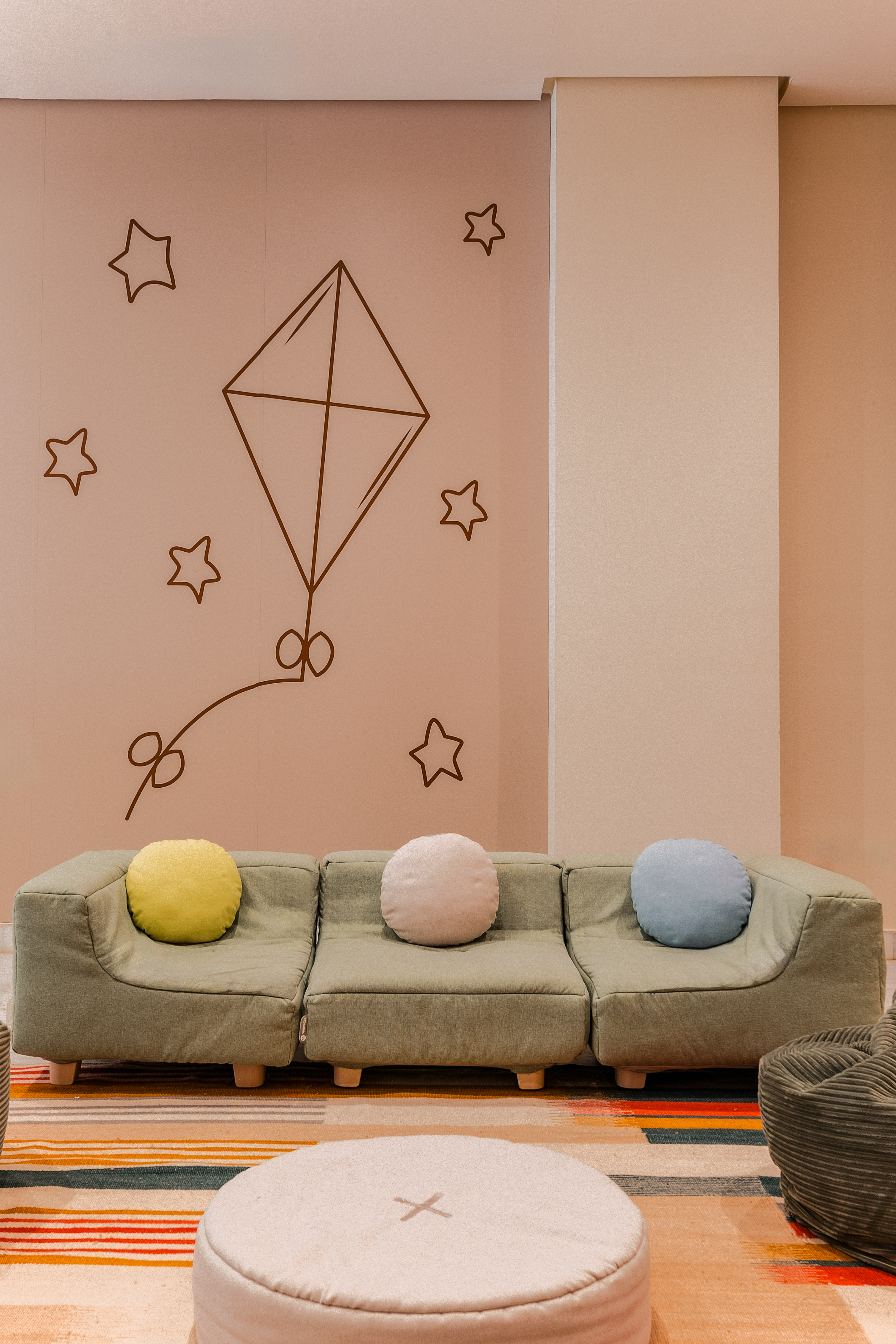 Children's play space: green modular sofa, colorful rug, kite, and star wall art.