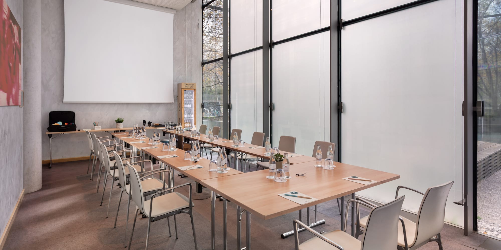 a long conference table with chairs and a projector screen