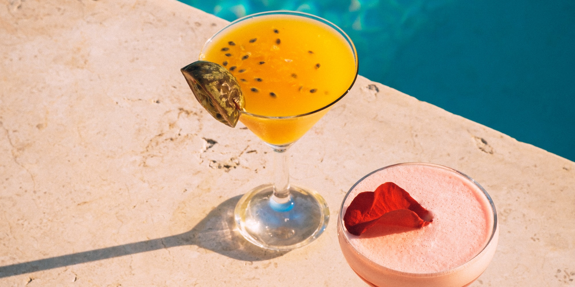 two glasses of drinks by a pool