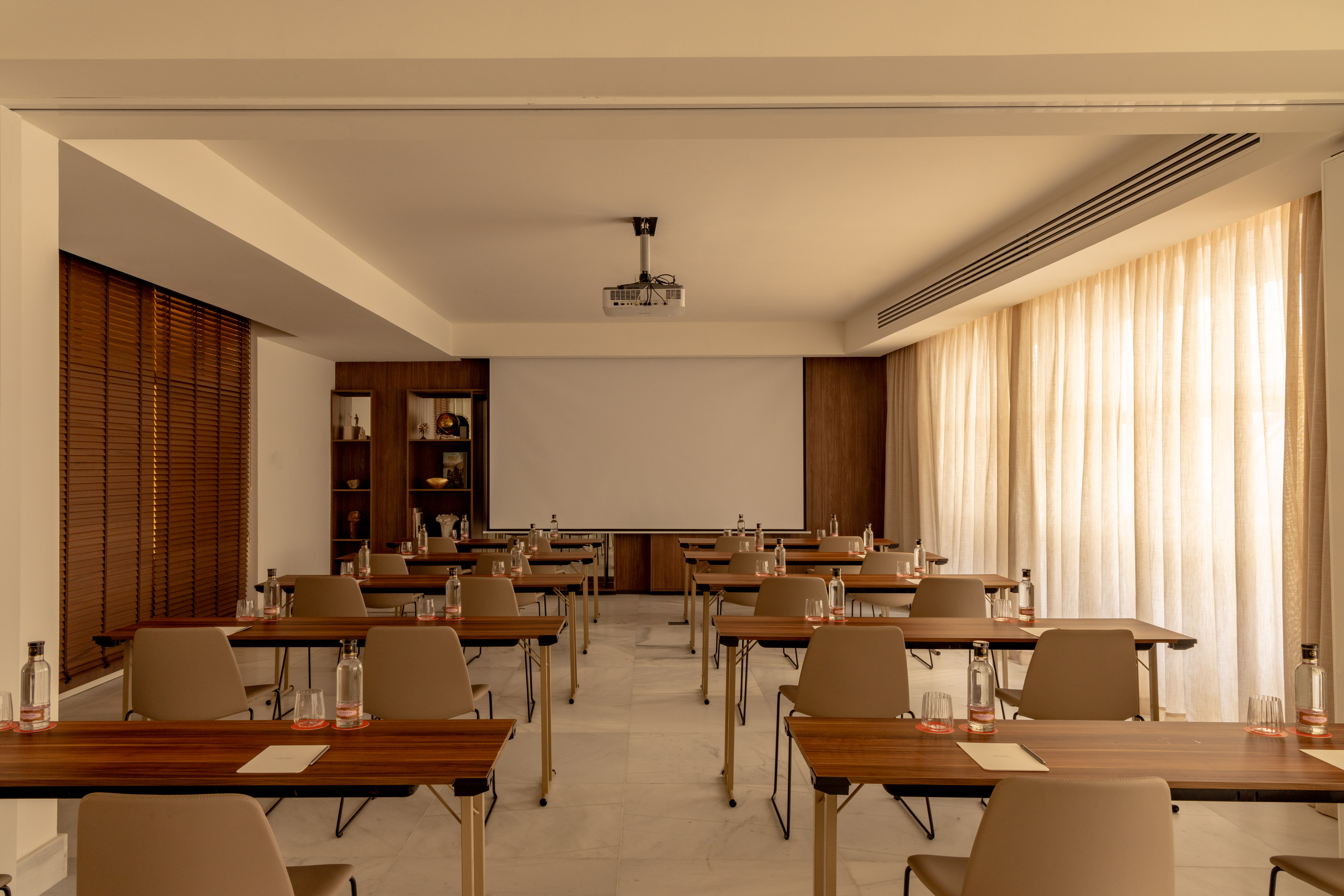Modern conference room setup with projector screen, tables, and chairs.