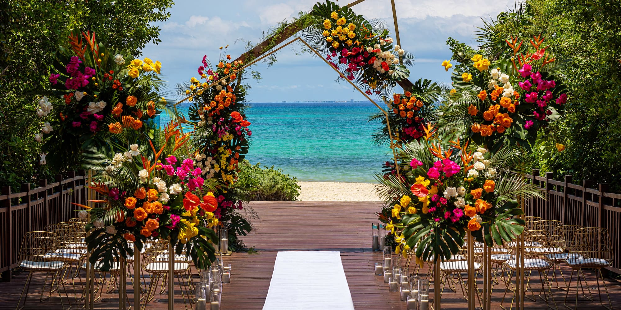 Beach wedding arch with colorful tropical flowers and turquoise ocean.