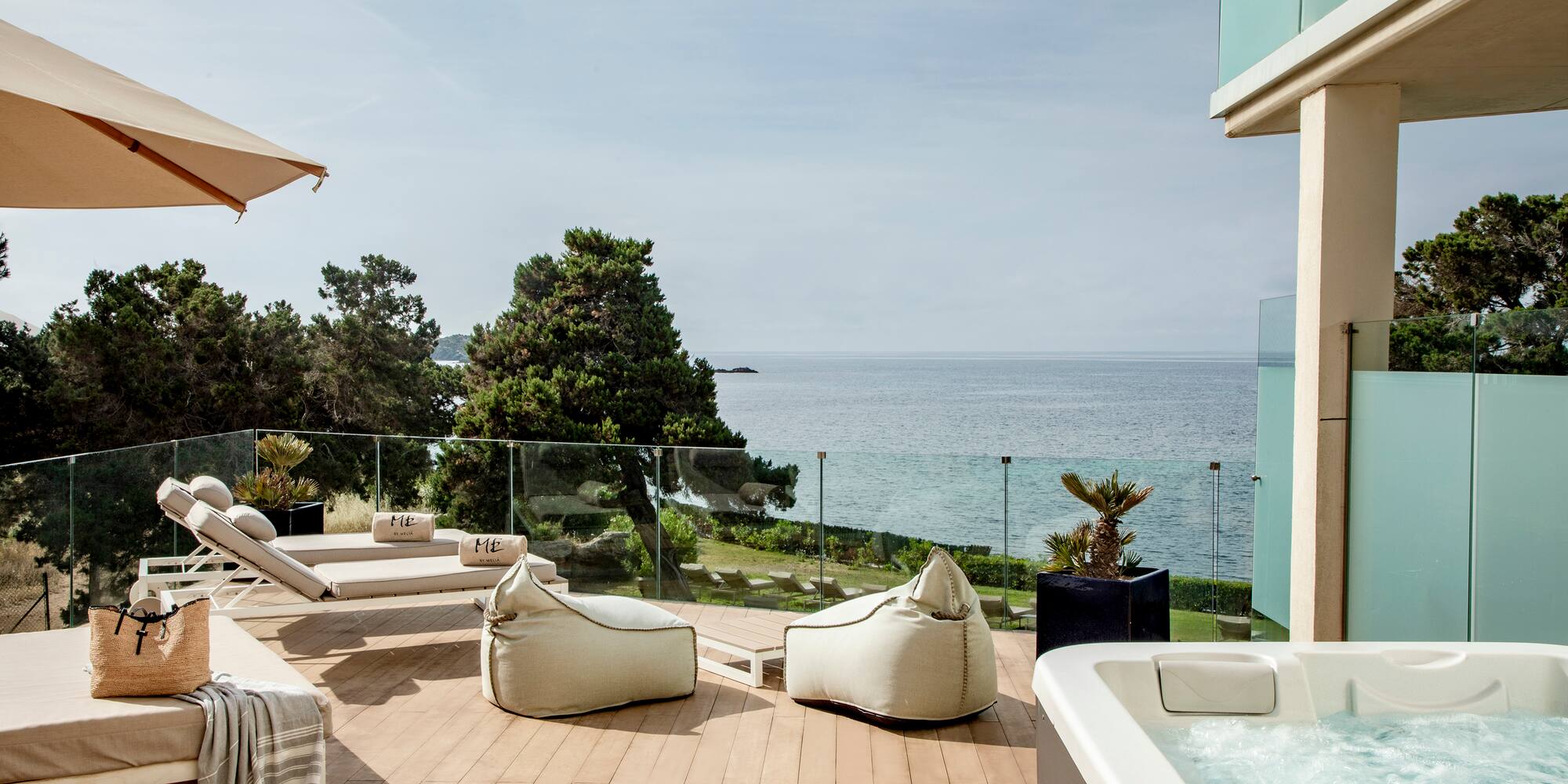 a deck with a hot tub and chairs and a large body of water