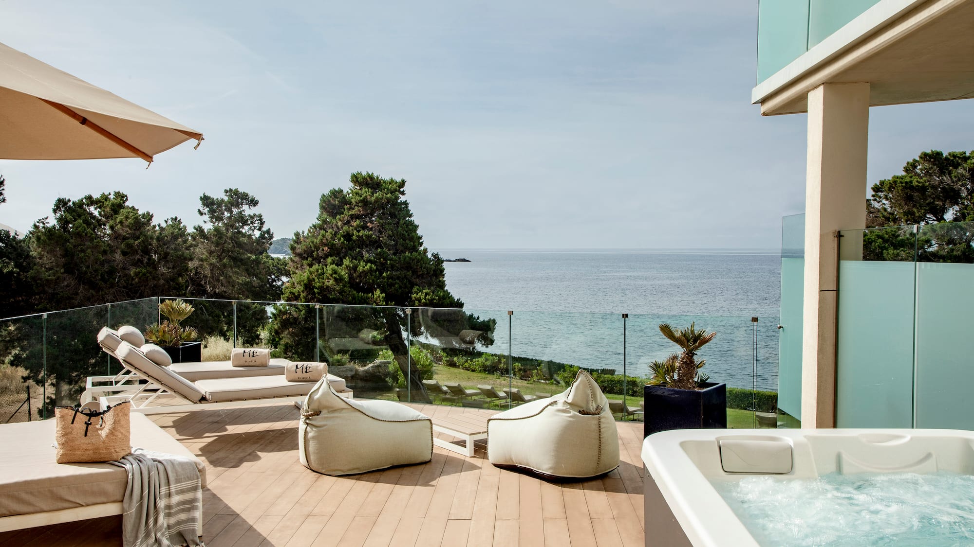 a deck with a hot tub and chairs and a large body of water