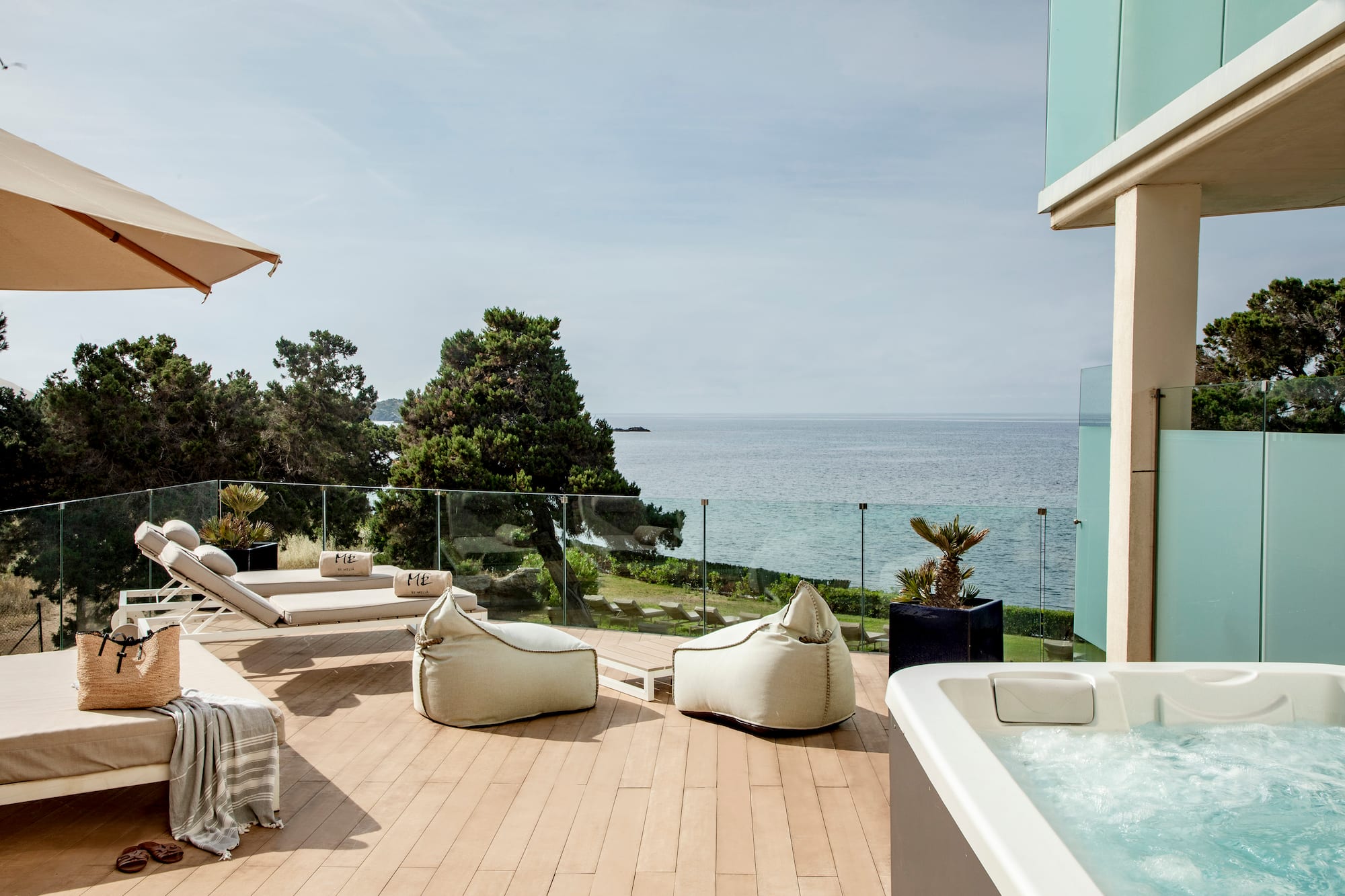 a deck with a hot tub and chairs and a large body of water