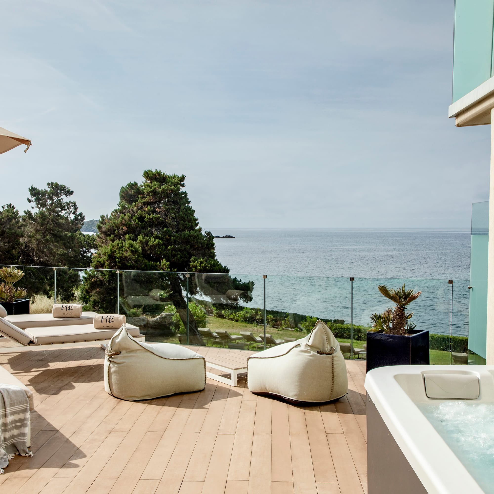 a deck with a hot tub and chairs and a large body of water