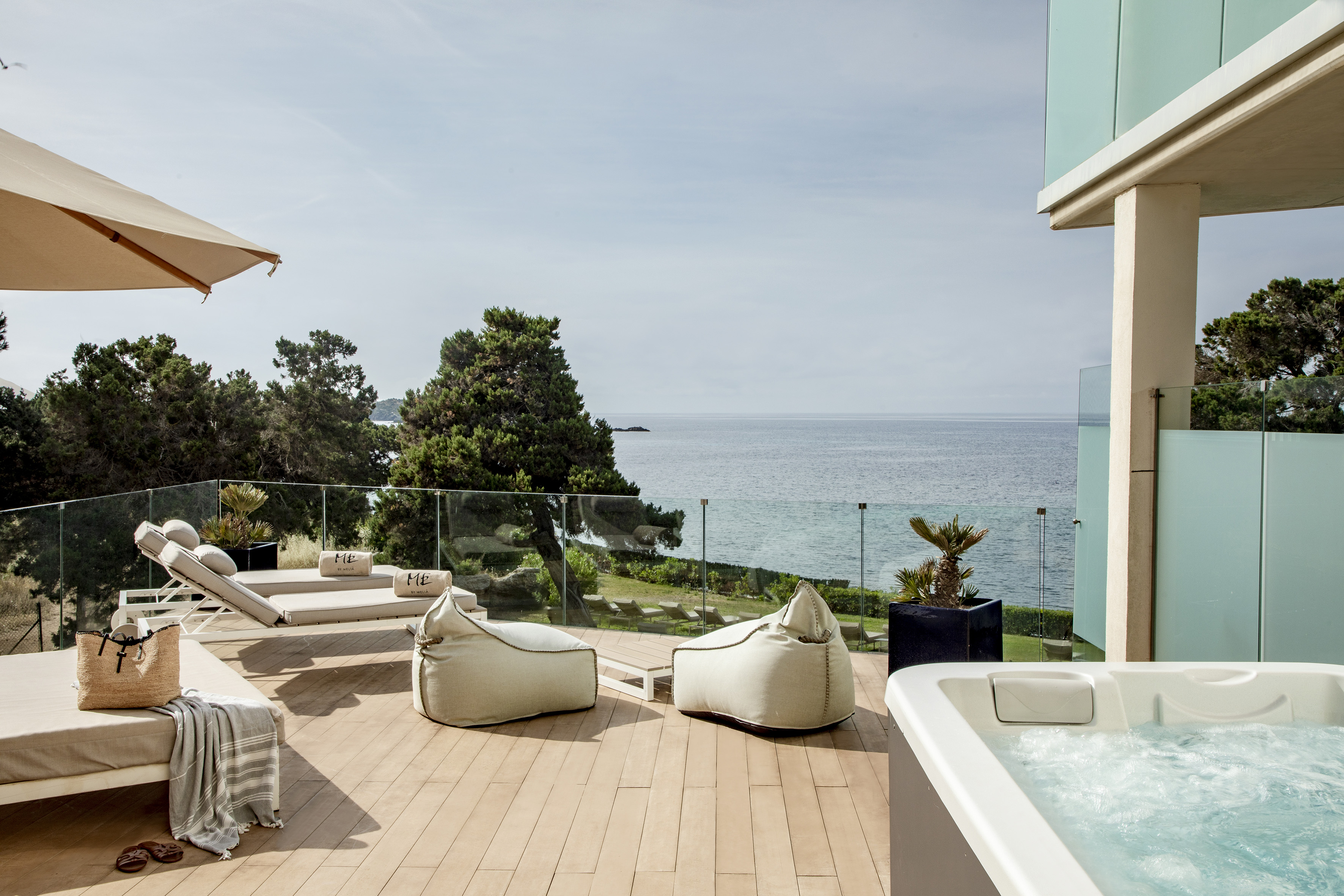 a deck with a hot tub and chairs and a large body of water