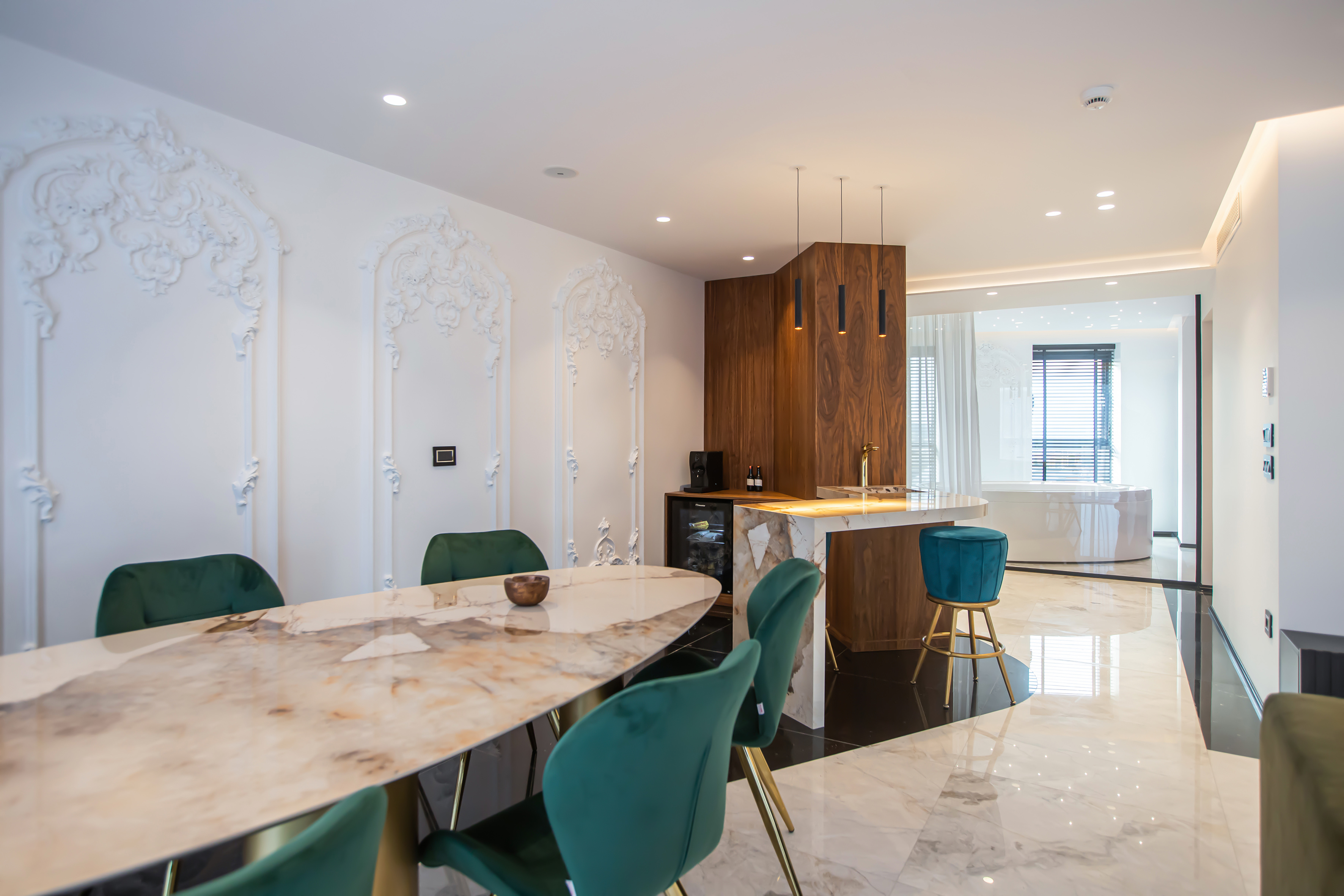 Modern luxury dining room and kitchen bar with marble table, green velvet chairs.