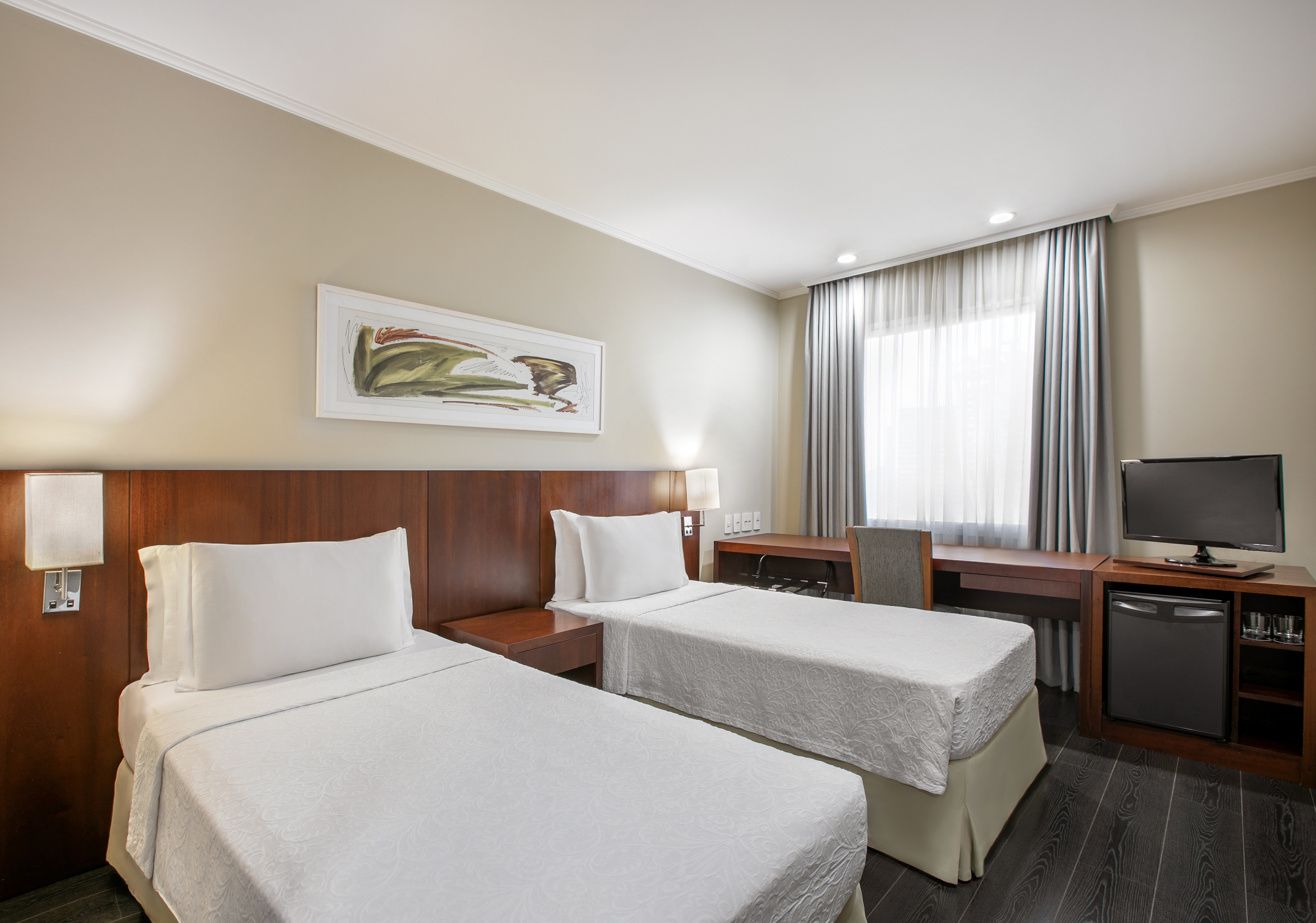 Modern hotel room with two twin beds, work desk, TV, and minibar.