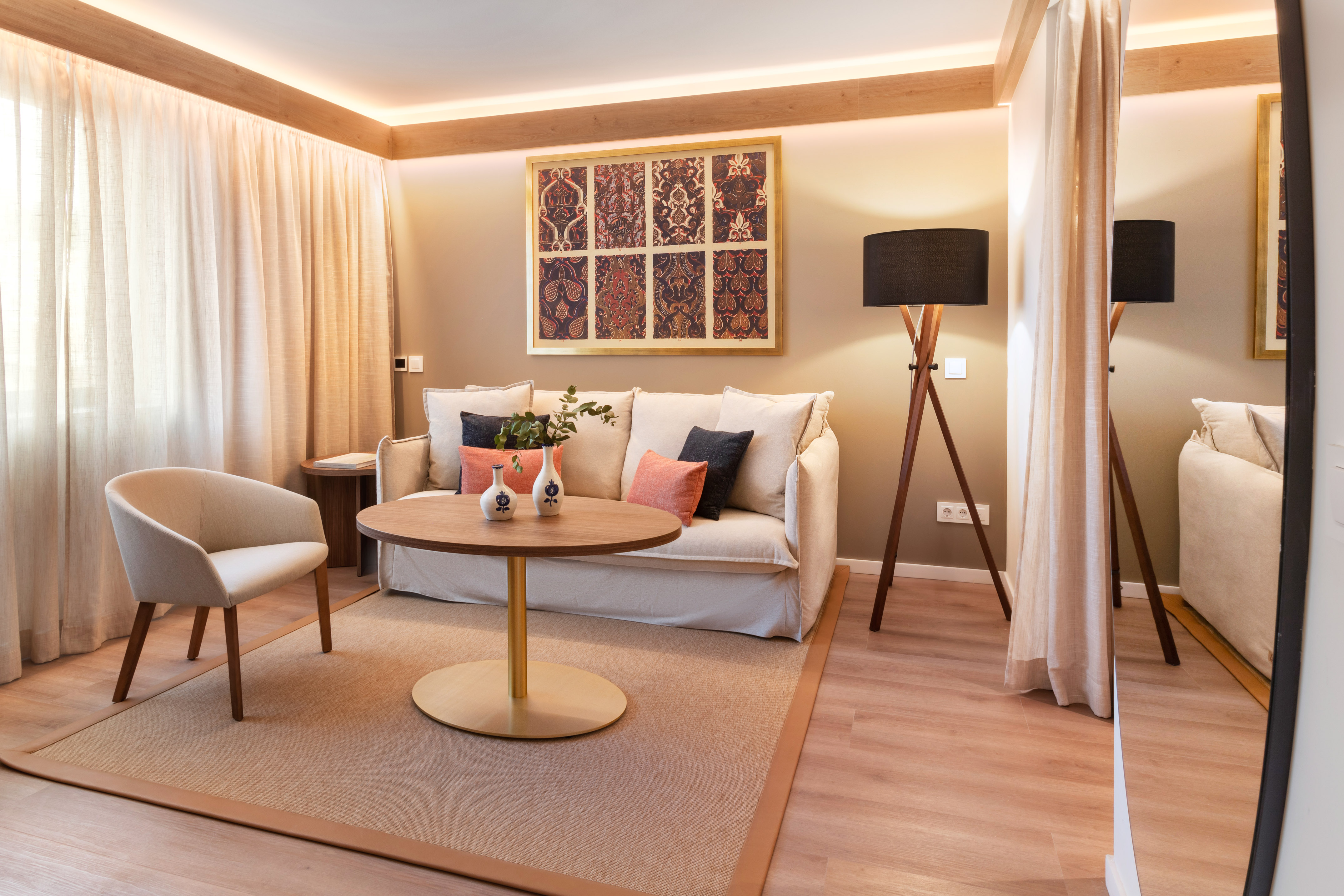 Cozy hotel living room with light sofa, patterned art, and warm lighting.