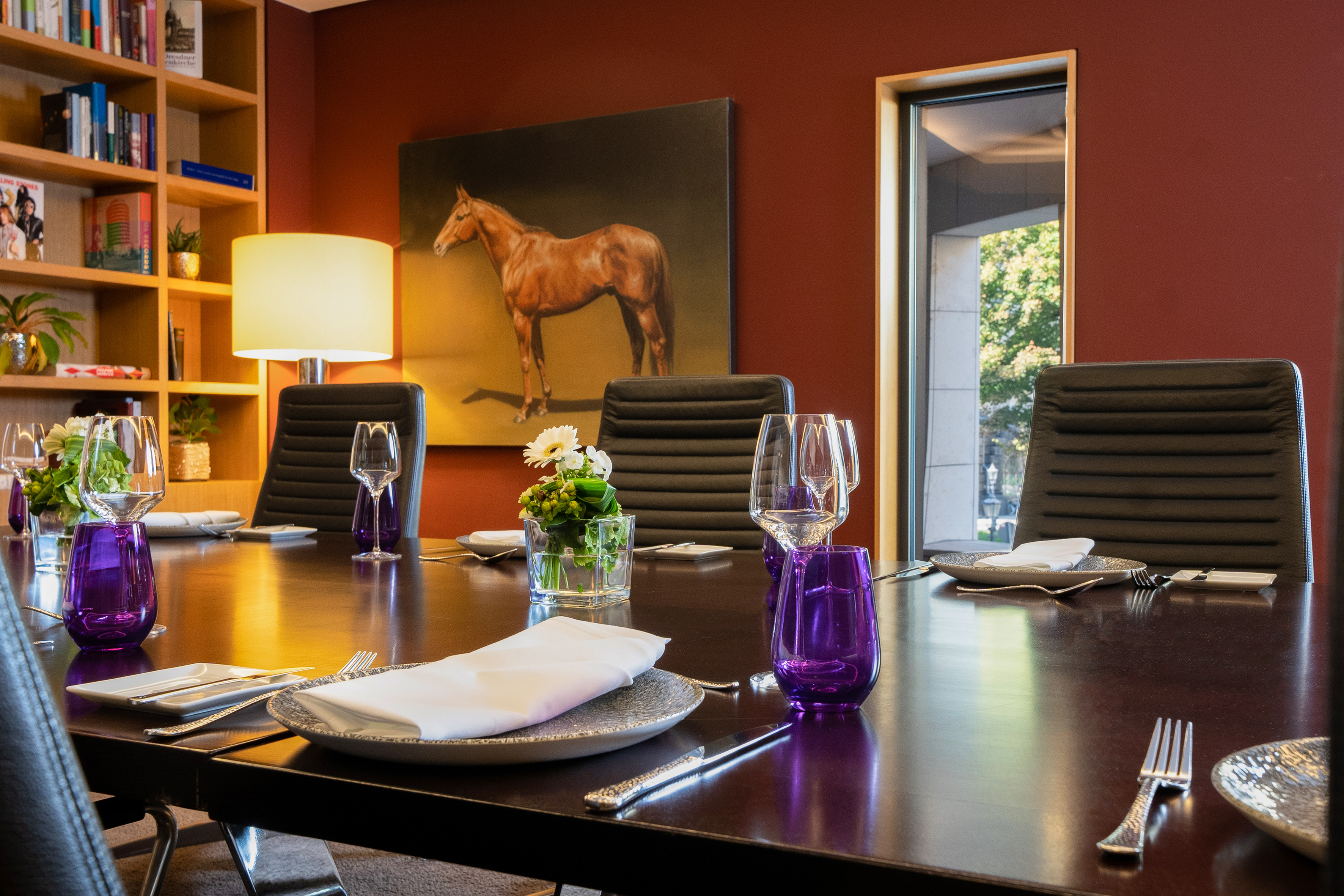Elegant dining/meeting room with long table, set places, horse art, and bookshelf. - CONLounge - INNSiDE Dresden, Dresden