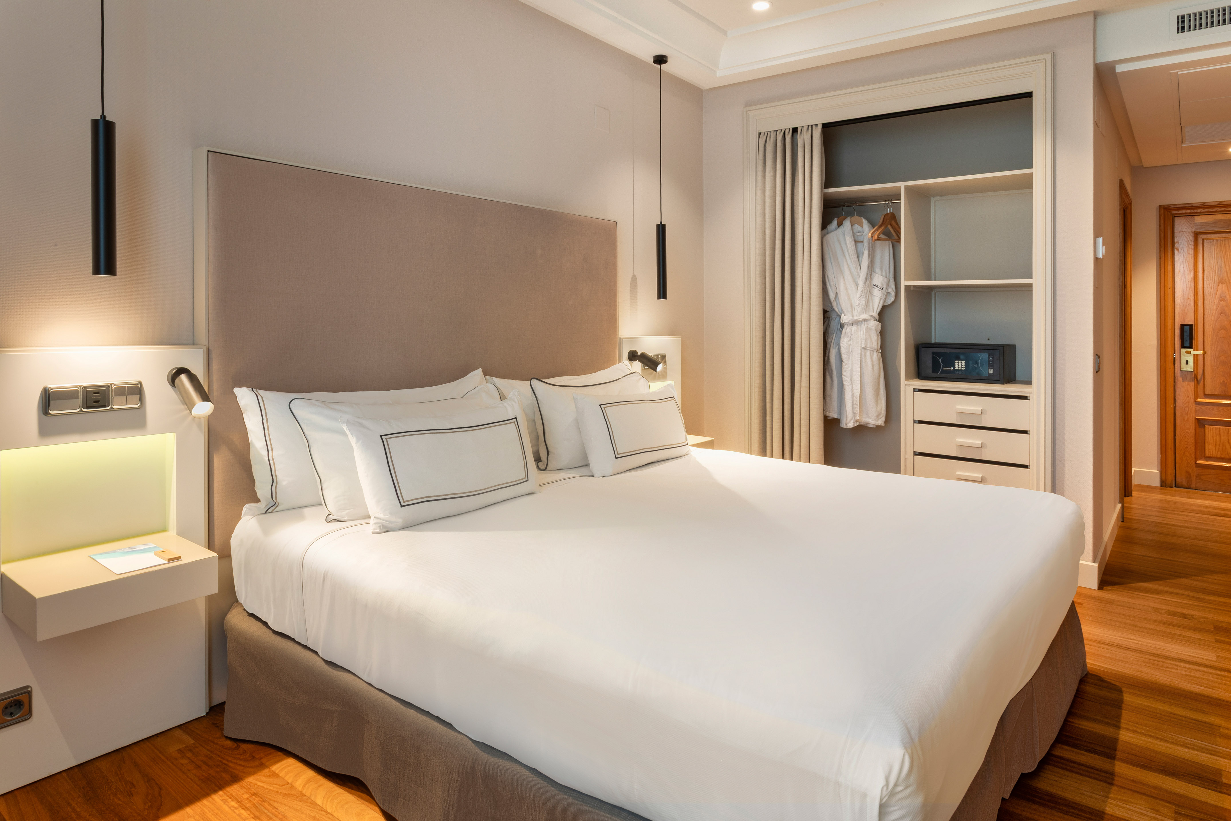 Modern hotel bedroom with king bed, built-in closet, and security safe.
