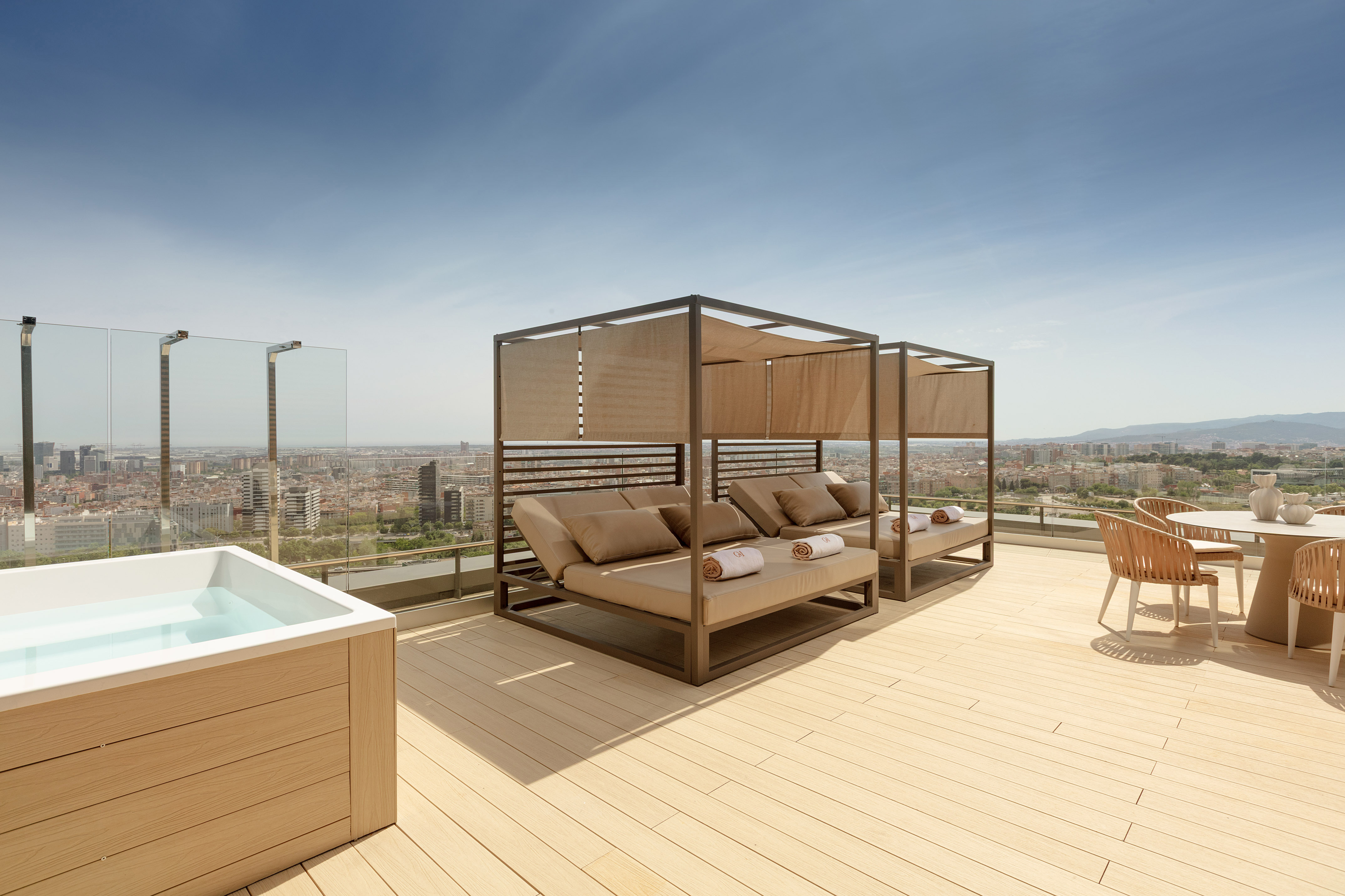 Rooftop terrace with hot tub, daybeds, and panoramic city views.