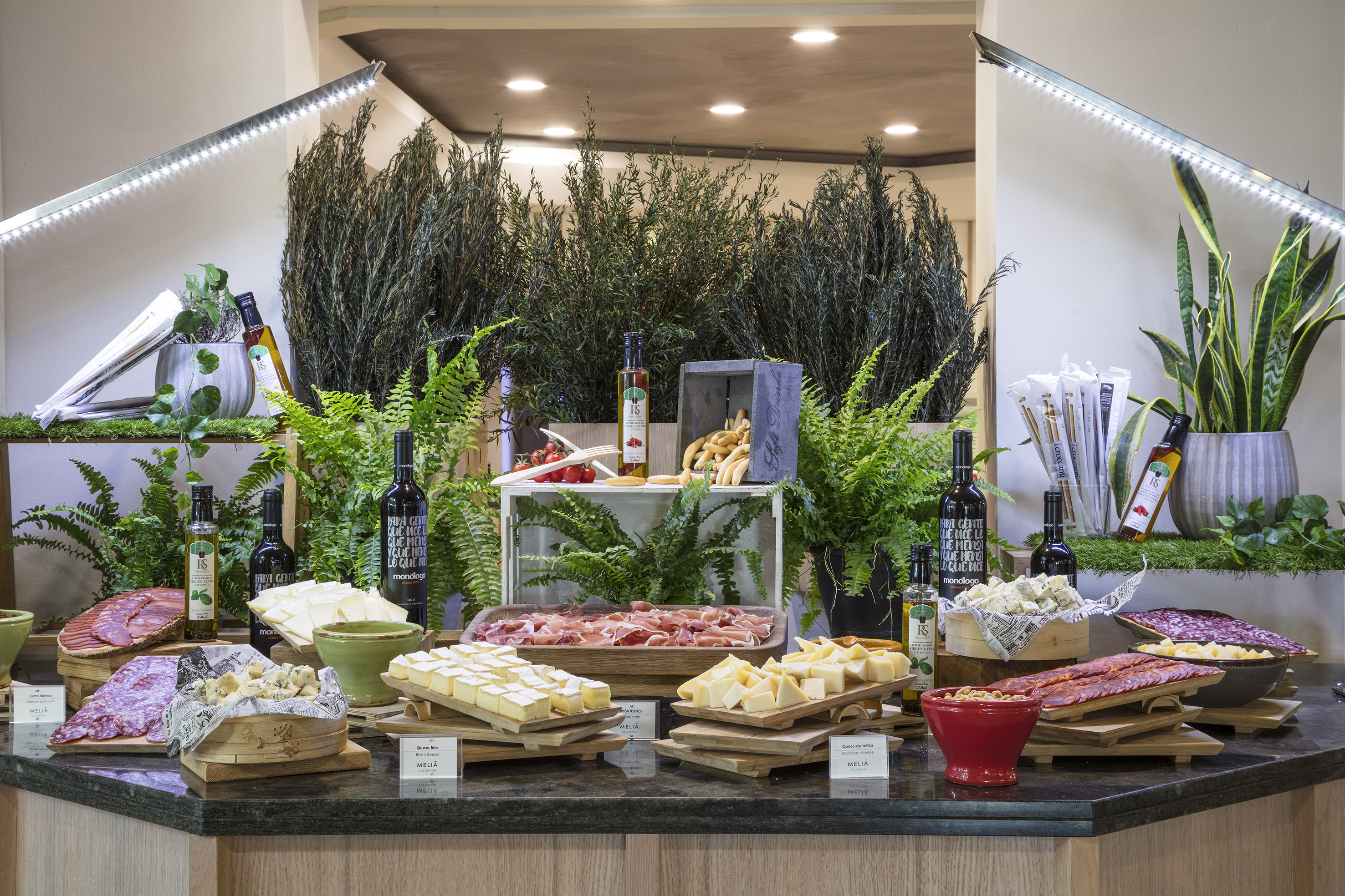 Abundant charcuterie and cheese buffet with meats, various cheeses, wines, and olive oils.
