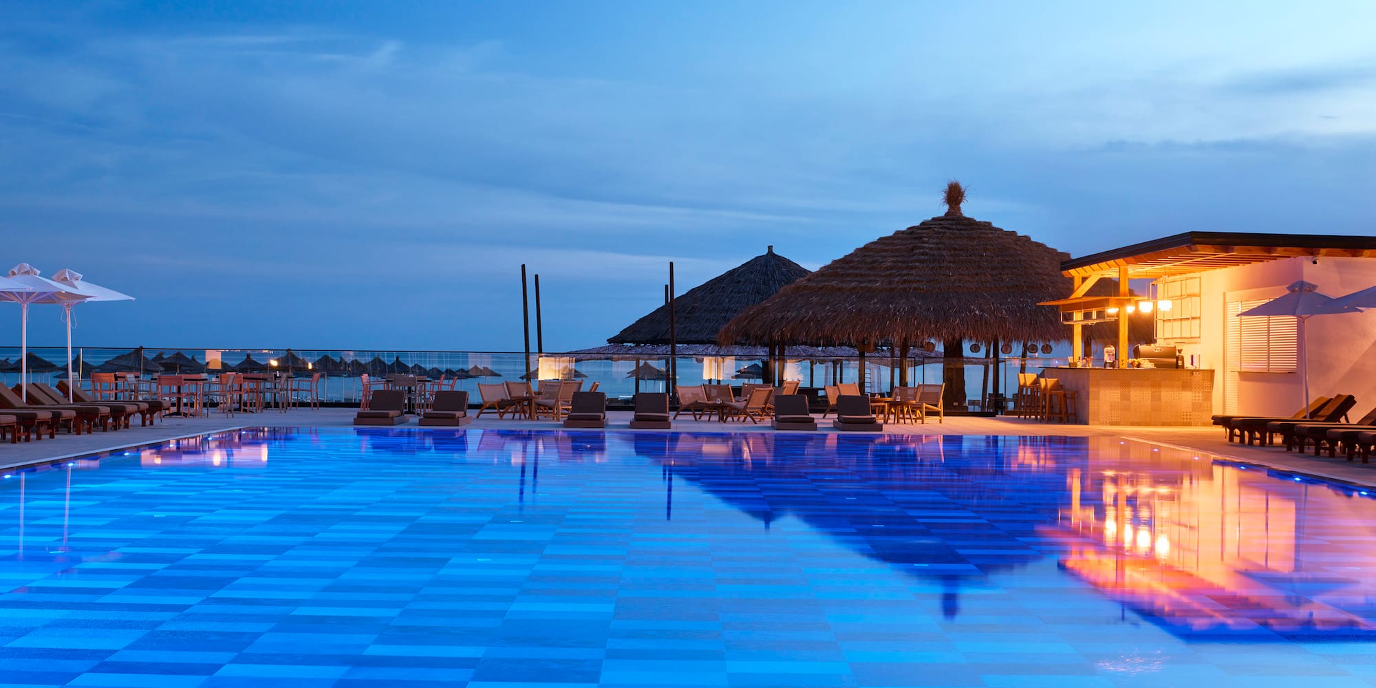 a pool with chairs and umbrellas and a gazebo