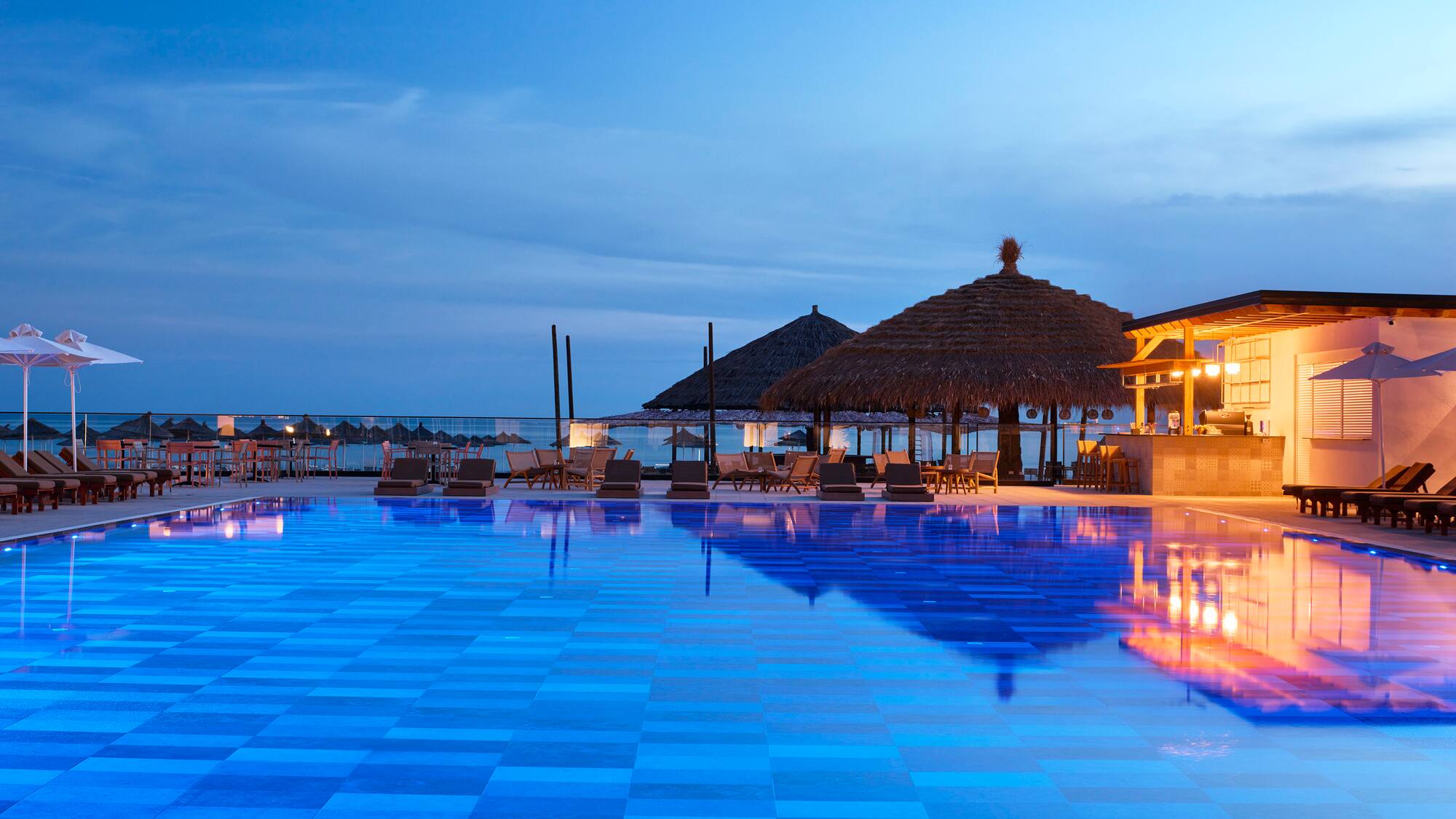a pool with chairs and umbrellas and a gazebo