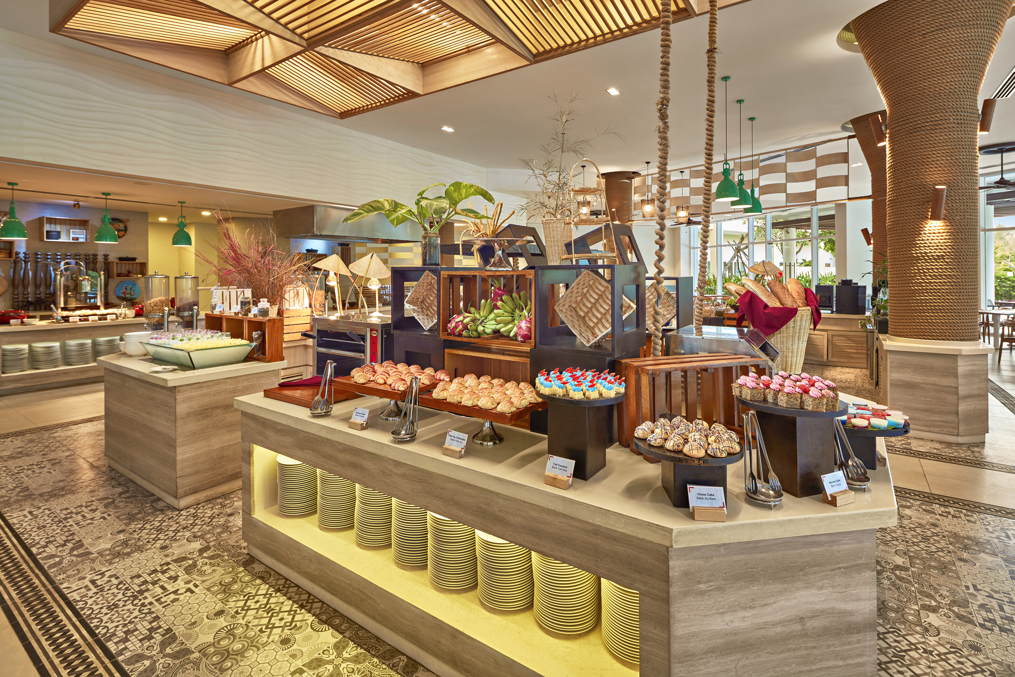 Resort buffet with pastries, tropical fruits, croissants, and cakes.