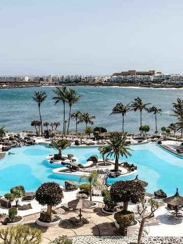 a pool with palm trees and a body of water