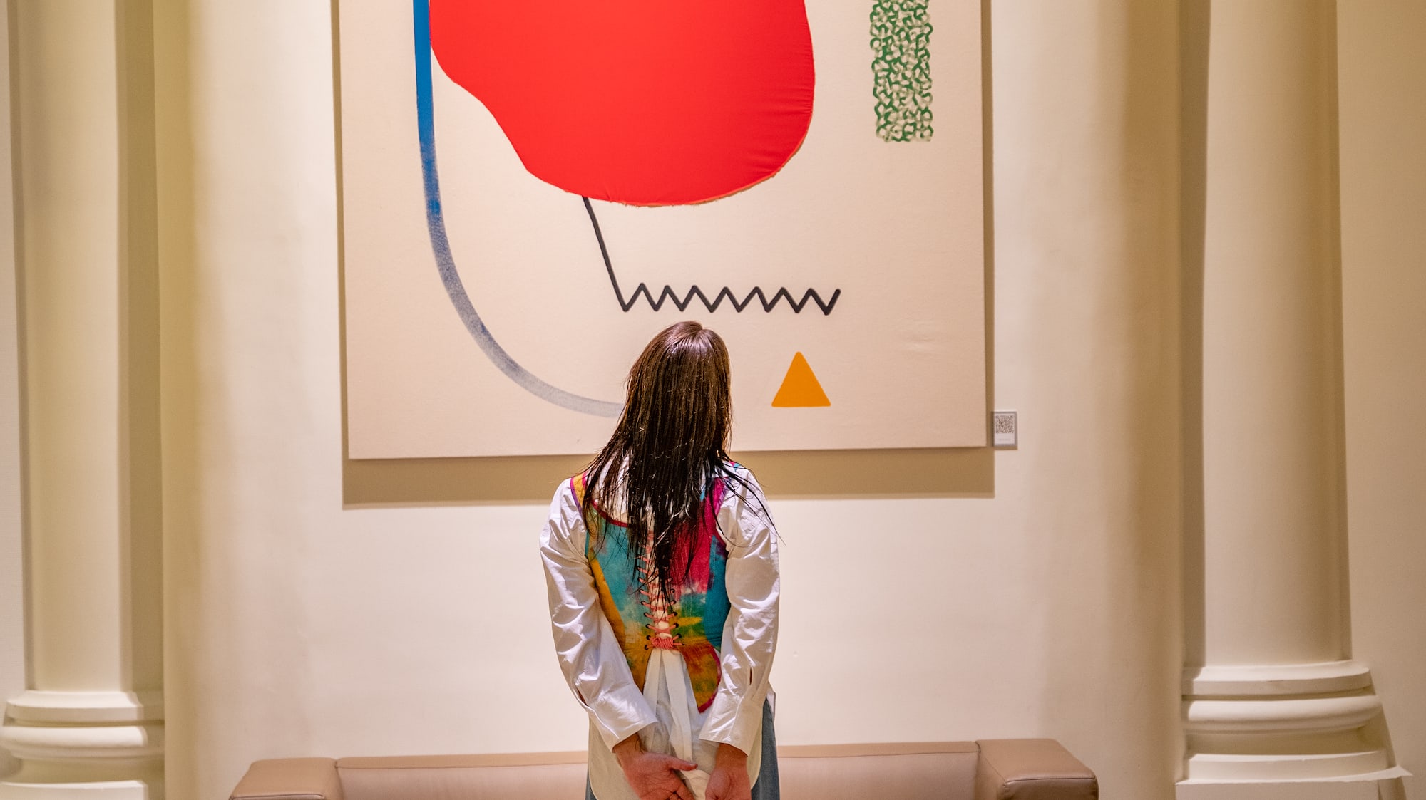 a woman standing in front of a painting