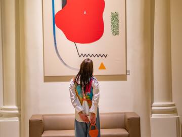 a woman standing in front of a painting