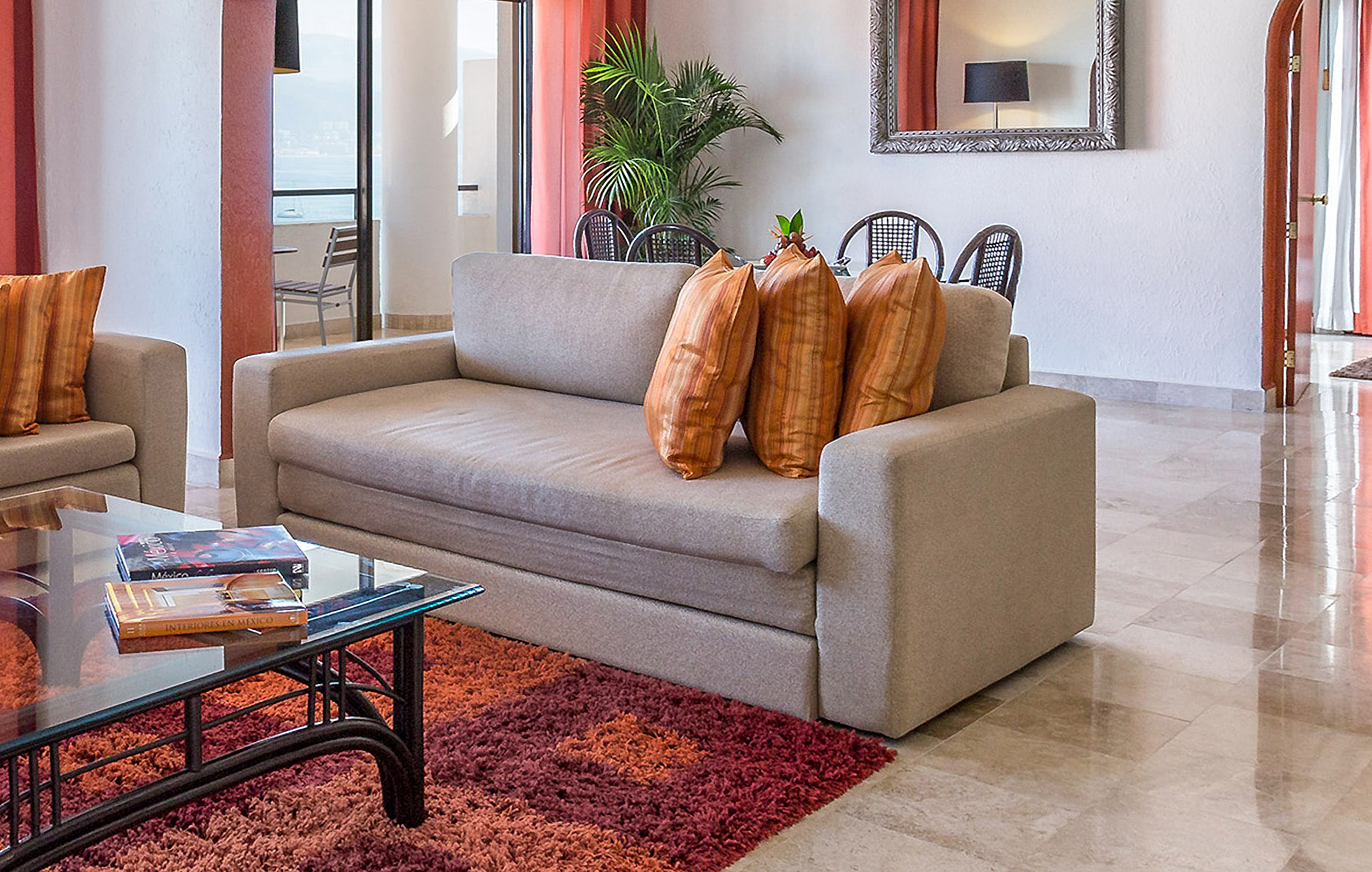 Modern living room with beige sofas, glass coffee table, and ocean view balcony.