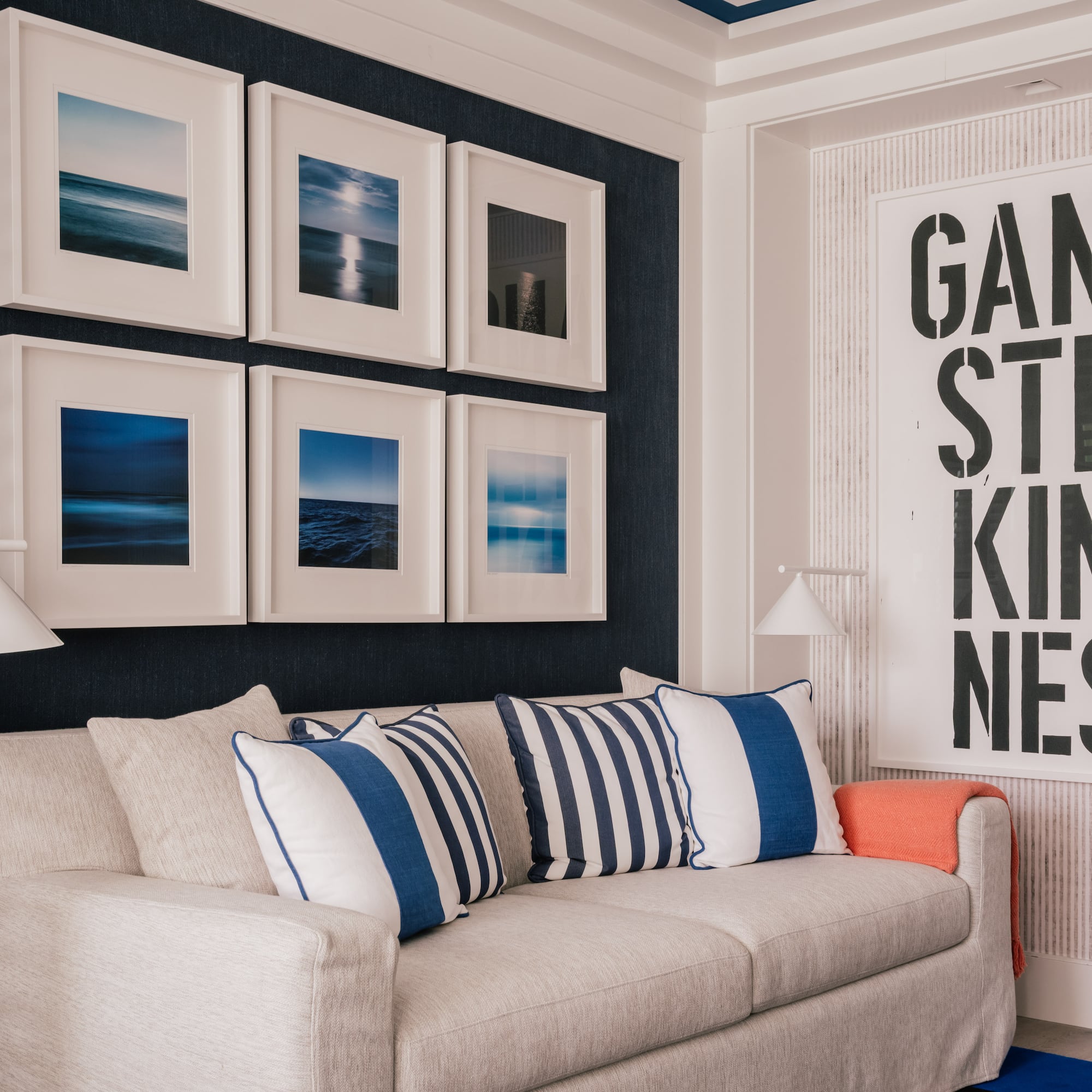 a couch with pillows and a lamp in a room with art on the wall