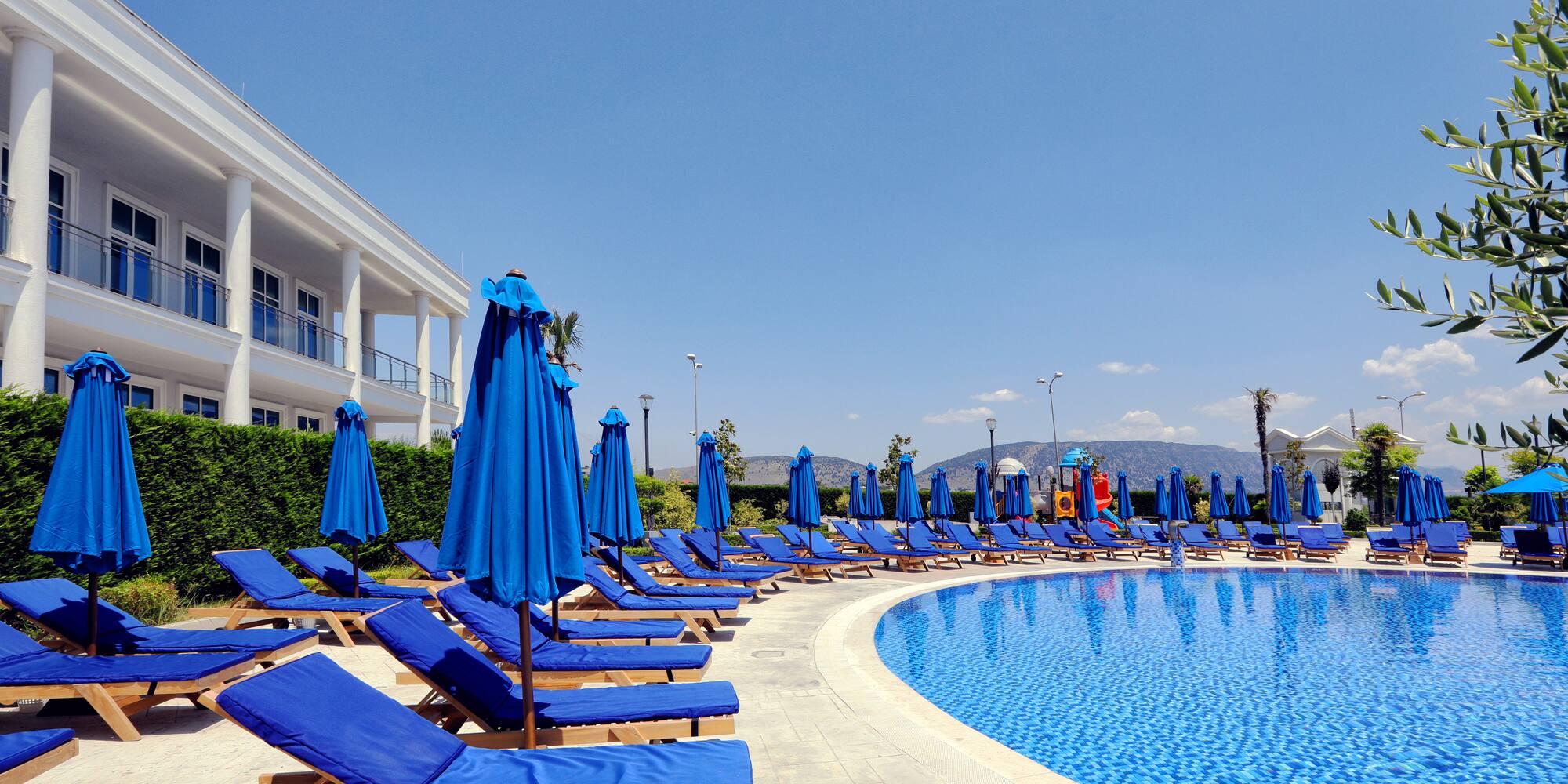 a pool with blue chairs and umbrellas