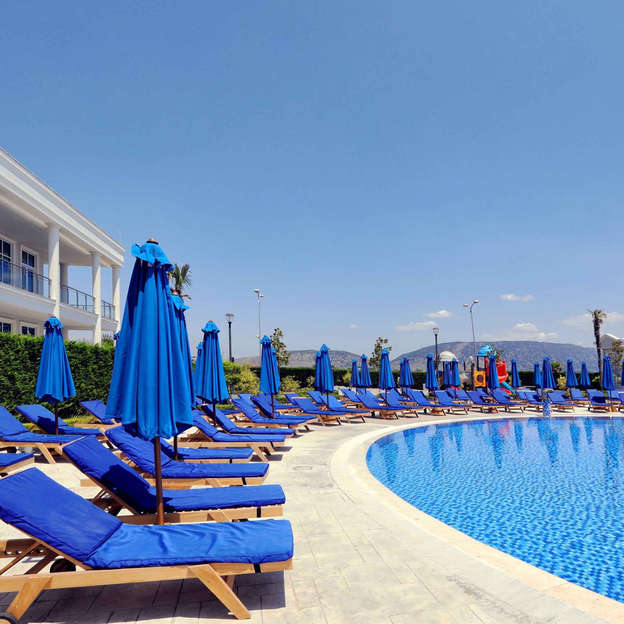 a pool with blue chairs and umbrellas