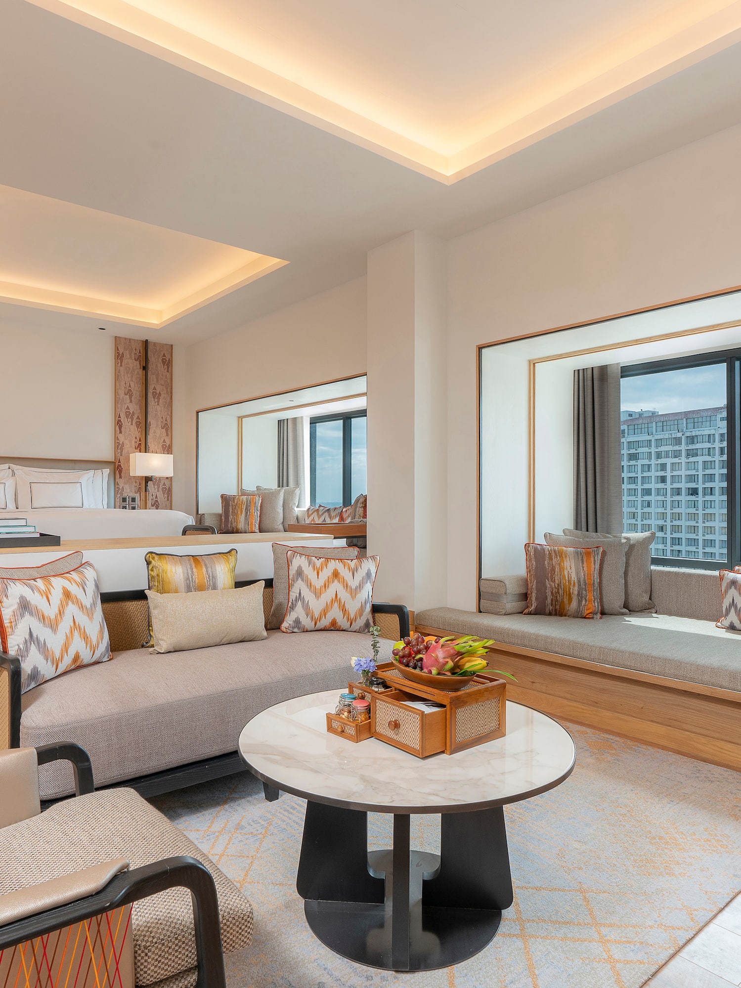 Modern hotel suite with living area, king bed, and panoramic city view.