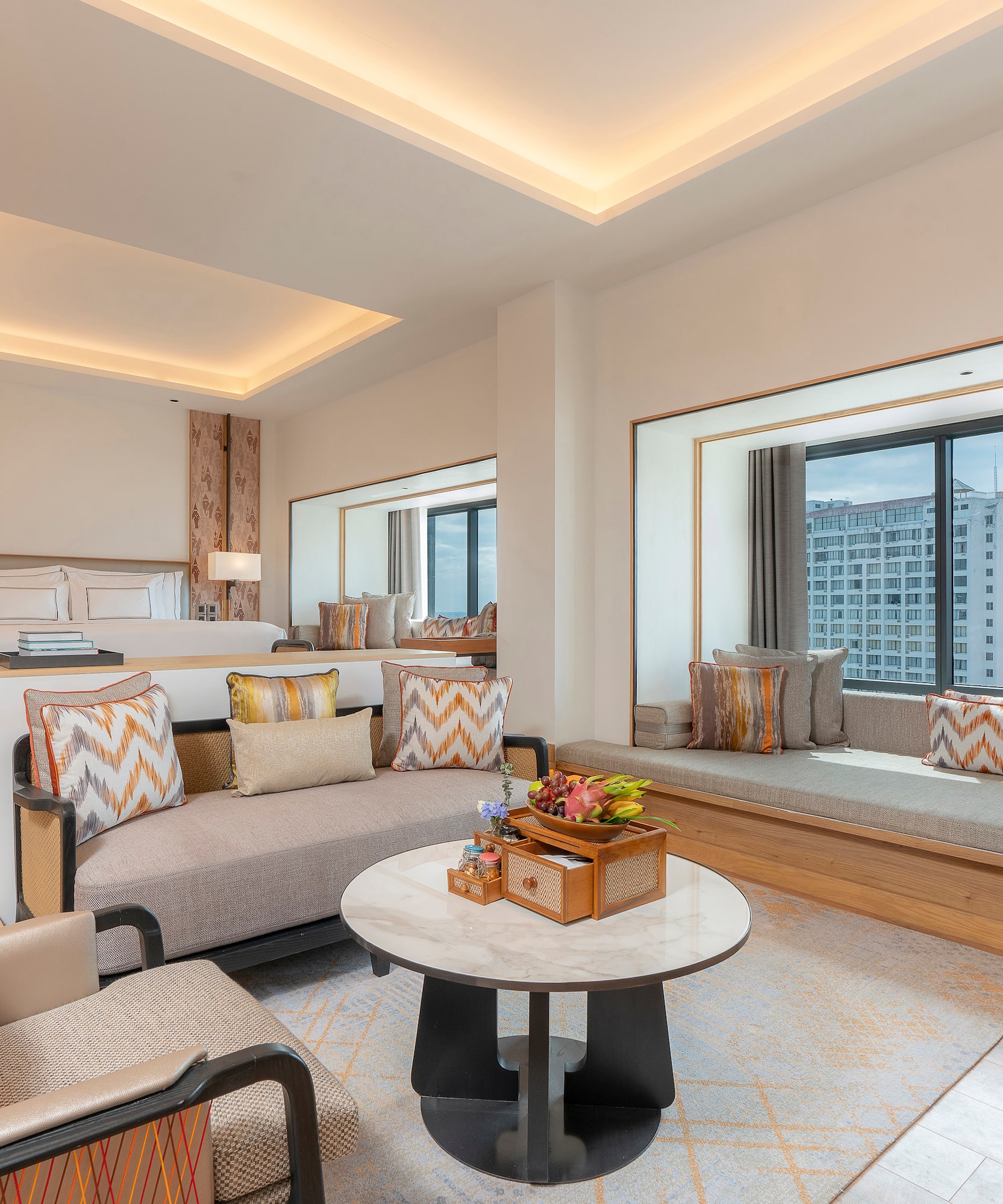 Modern hotel suite with living area, king bed, and panoramic city view.