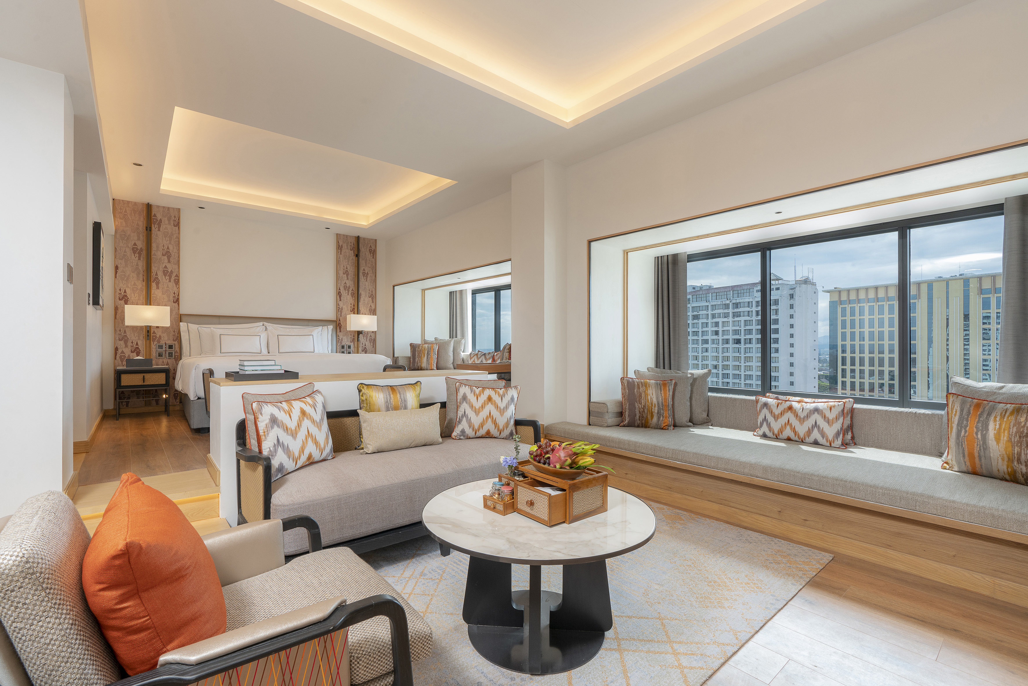 Modern hotel suite with living area, king bed, and panoramic city view.