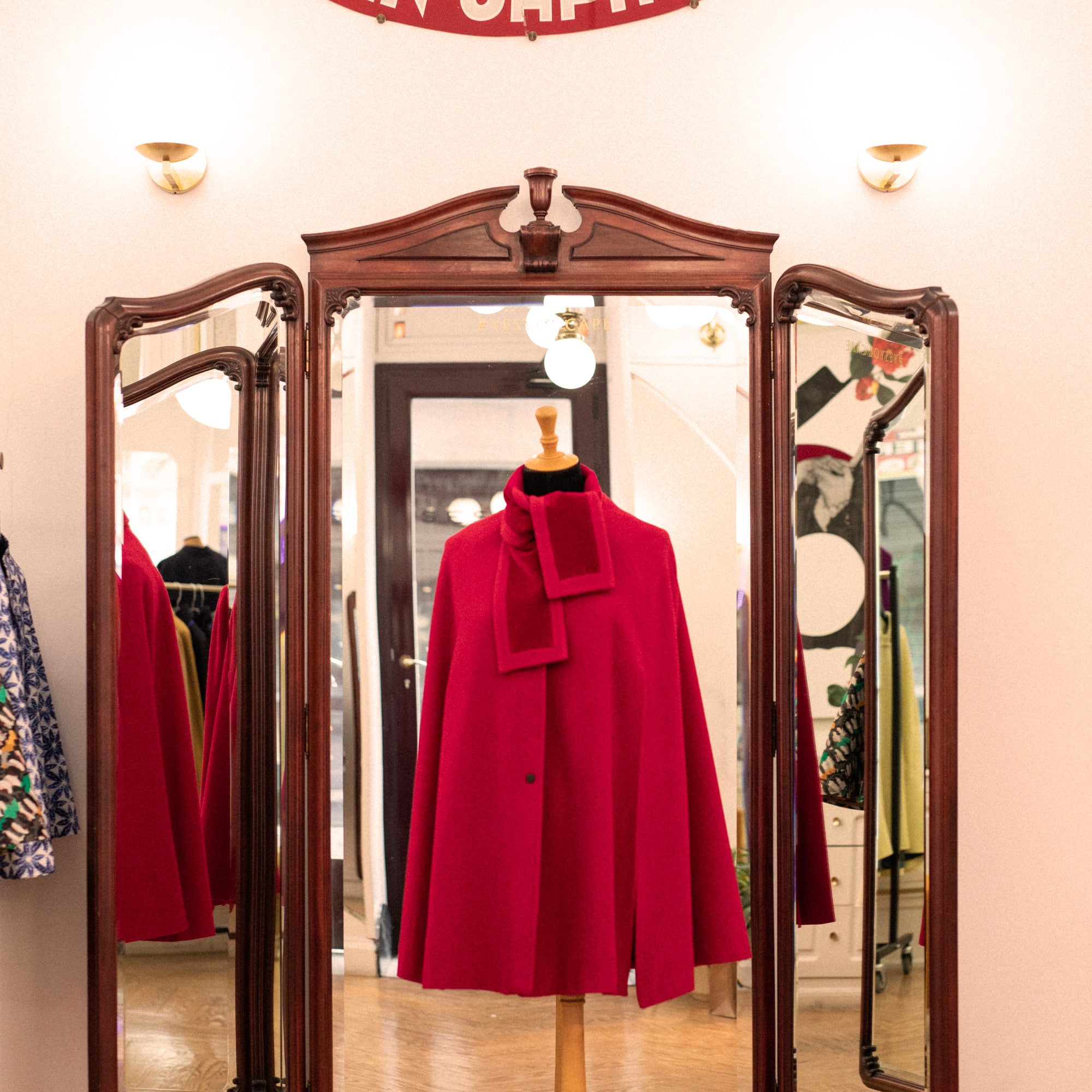 a red coat on a stand in front of a mirror