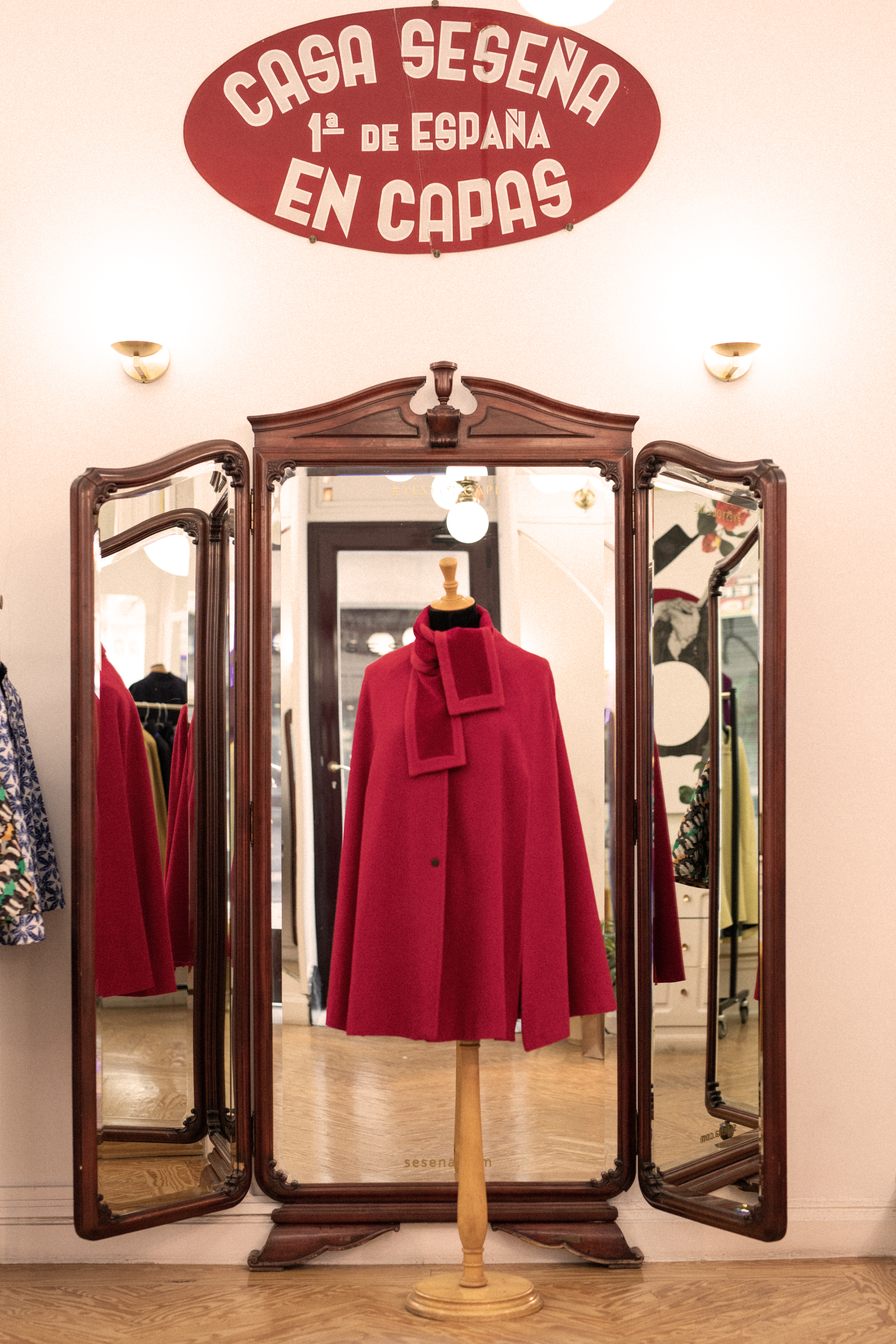a red coat on a stand in front of a mirror