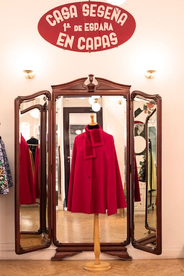 a red coat on a stand in front of a mirror
