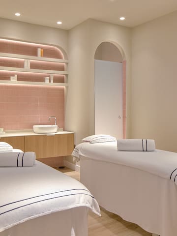 a room with beds and pink tile walls
