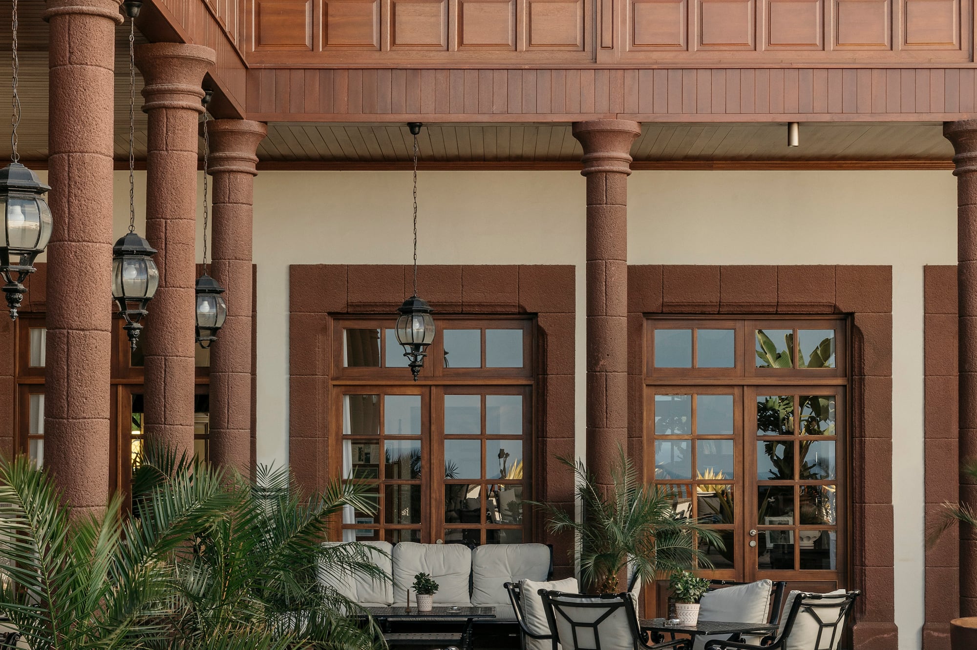 Hotel patio with outdoor seating, wooden balconies, and stone columns.