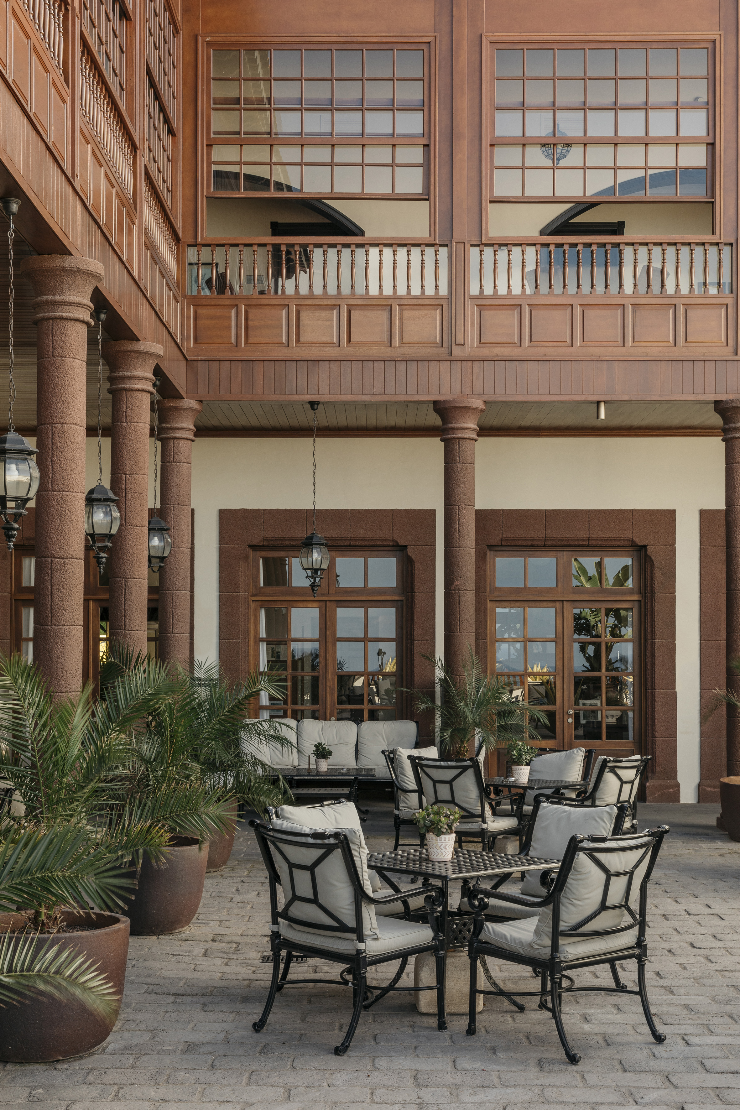 Hotel patio with outdoor seating, wooden balconies, and stone columns.