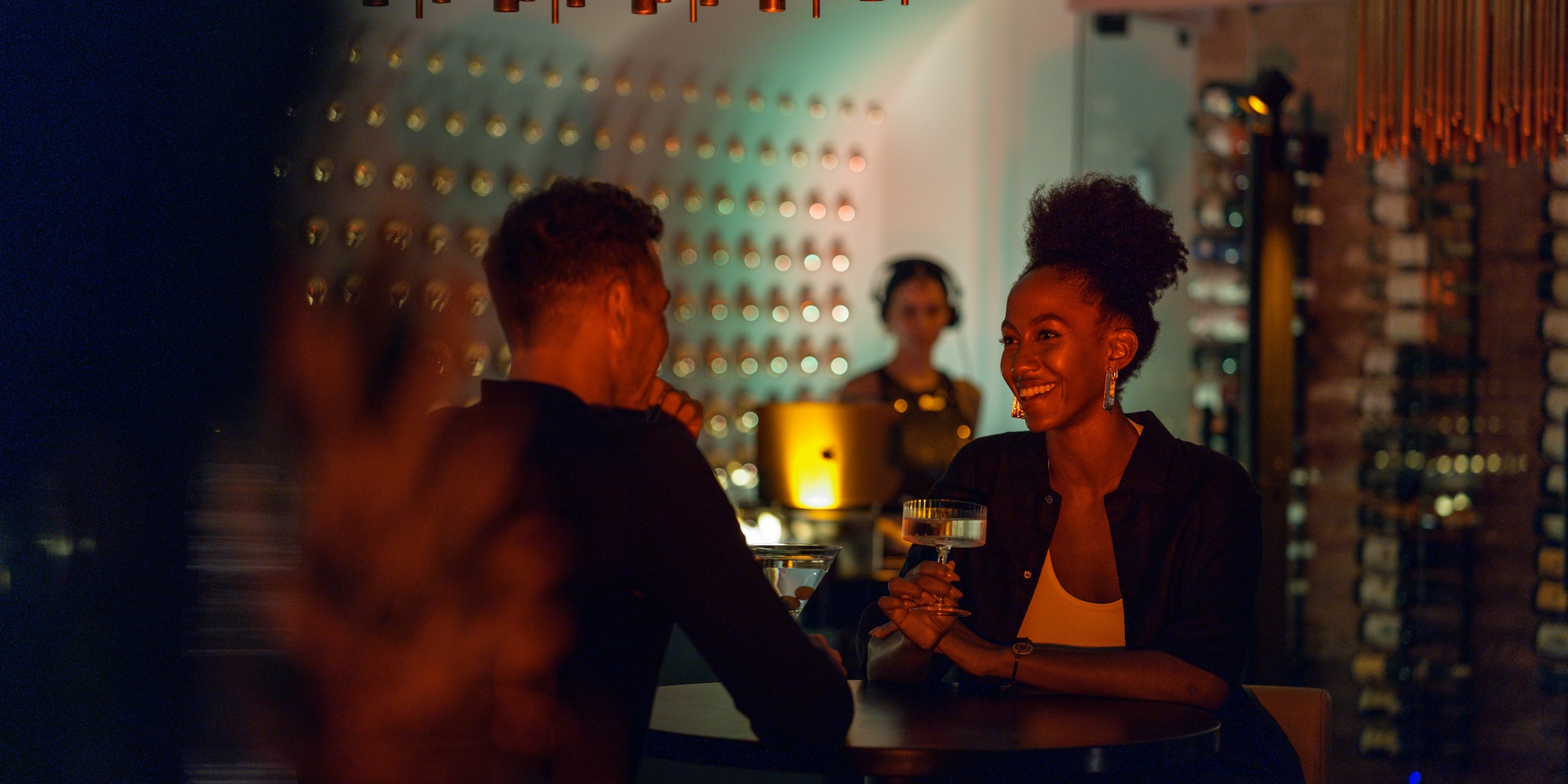 a woman holding a drink with a man in the background