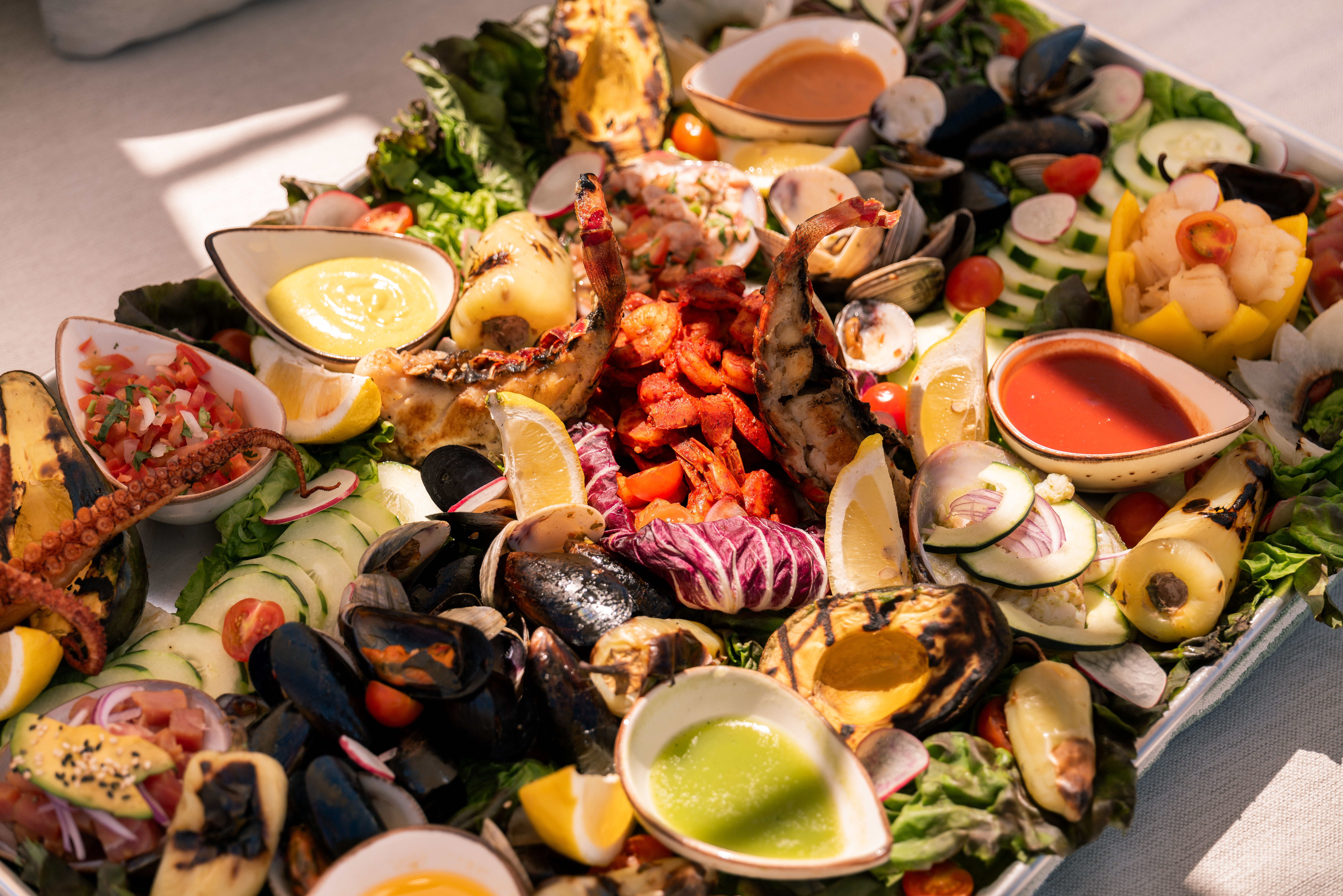 a plate of seafood with sauces and vegetables