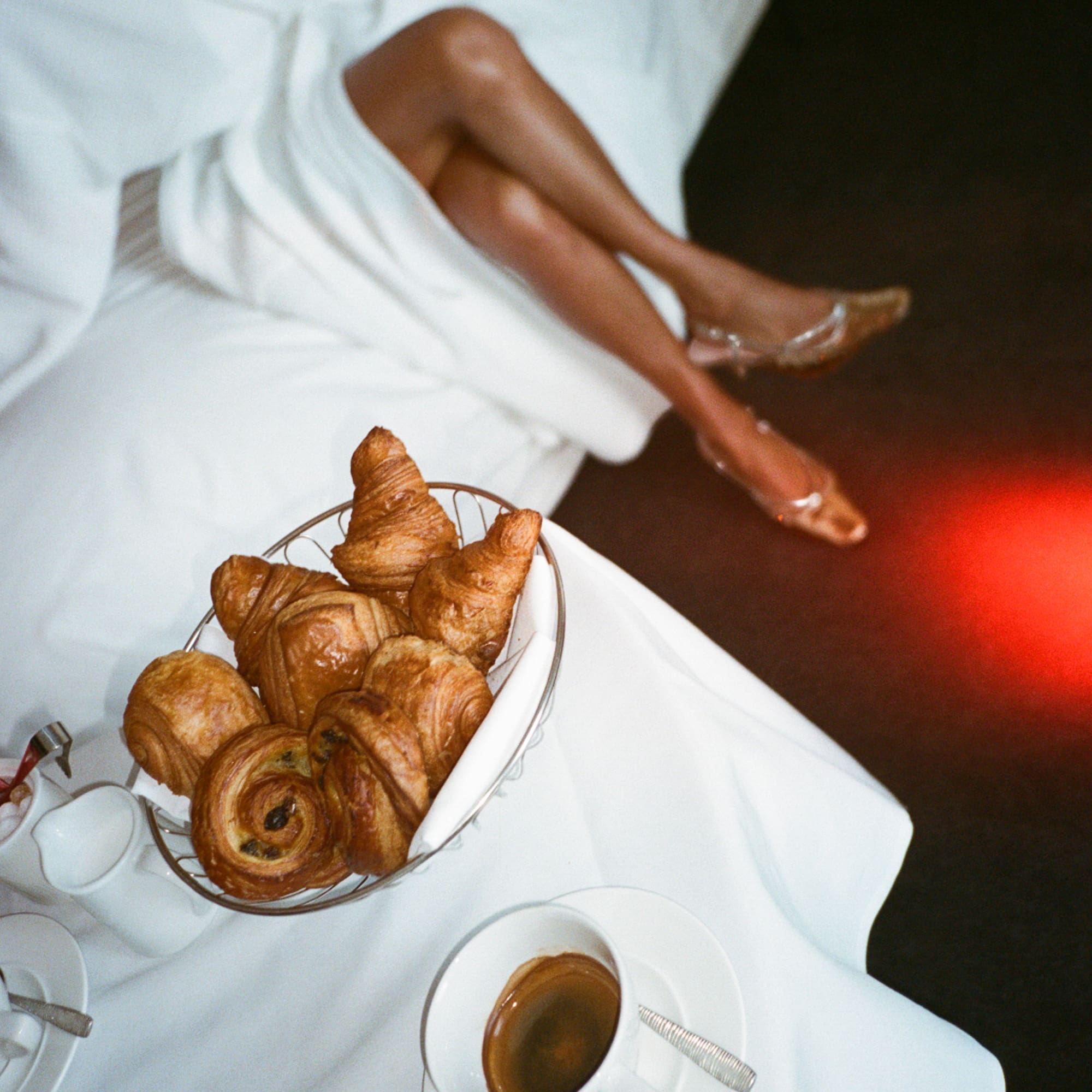 A woman rests on a bed, enjoying a bowl of pastries.