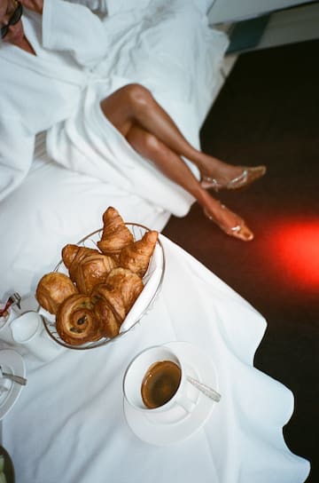 a woman lying on a bed with a bowl of pastries