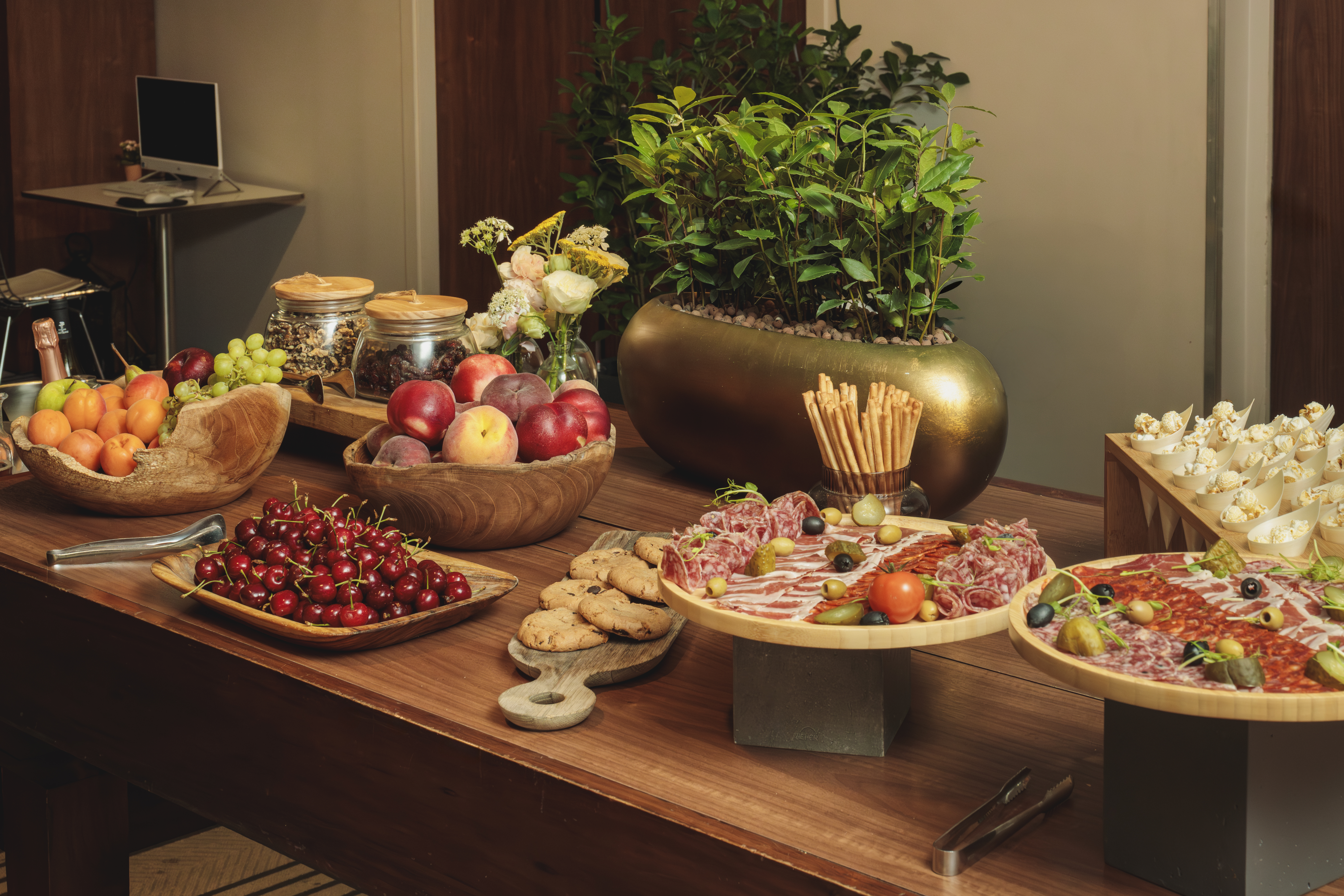 Gourmet buffet table with charcuterie, fresh fruits, cookies, and snacks.
