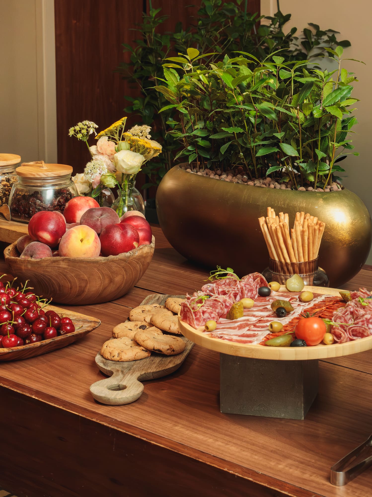 Gourmet buffet table with charcuterie, fresh fruits, cookies, and snacks.