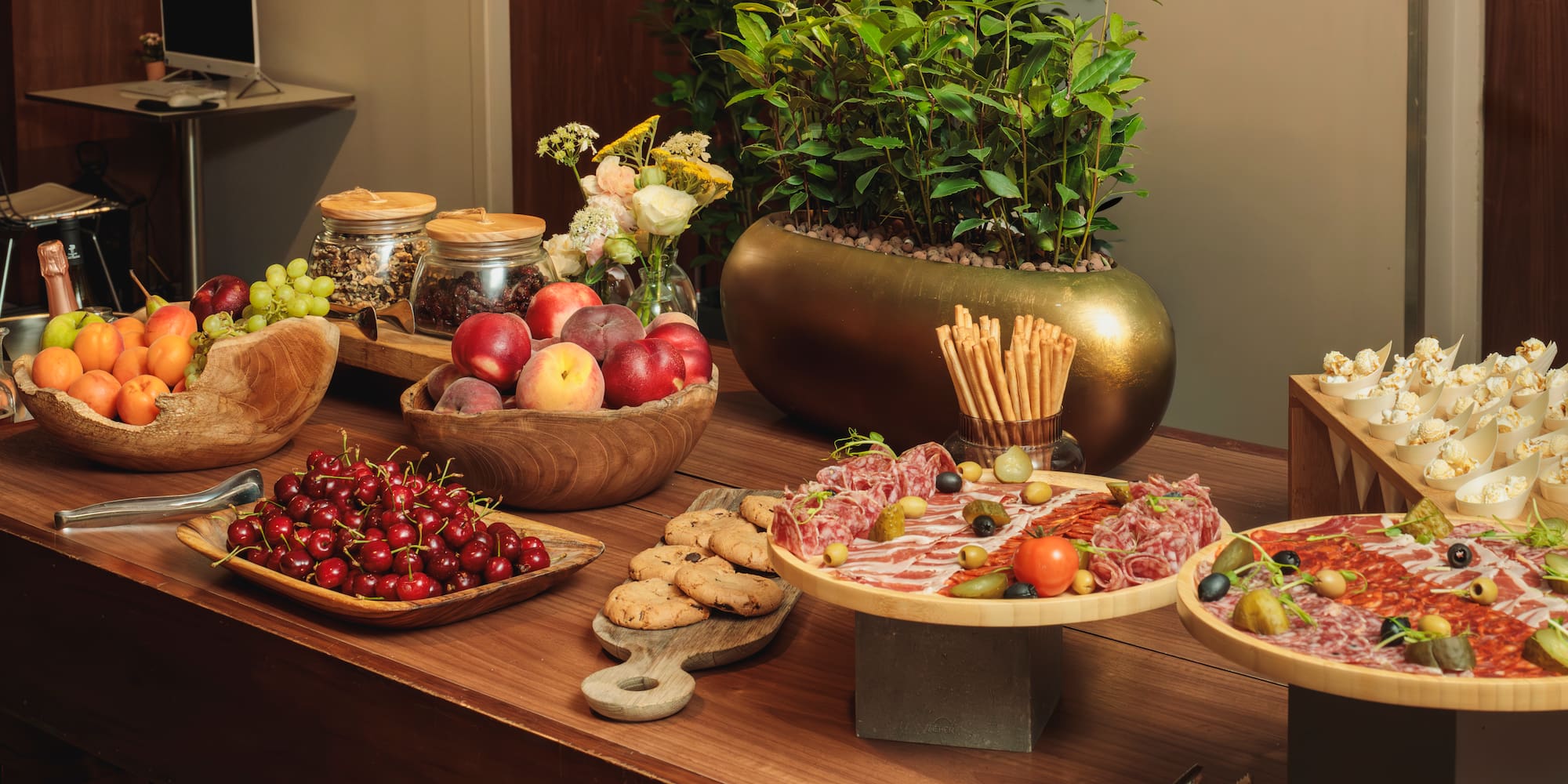 Gourmet buffet with fresh fruit, charcuterie, cookies, breadsticks, and popcorn.