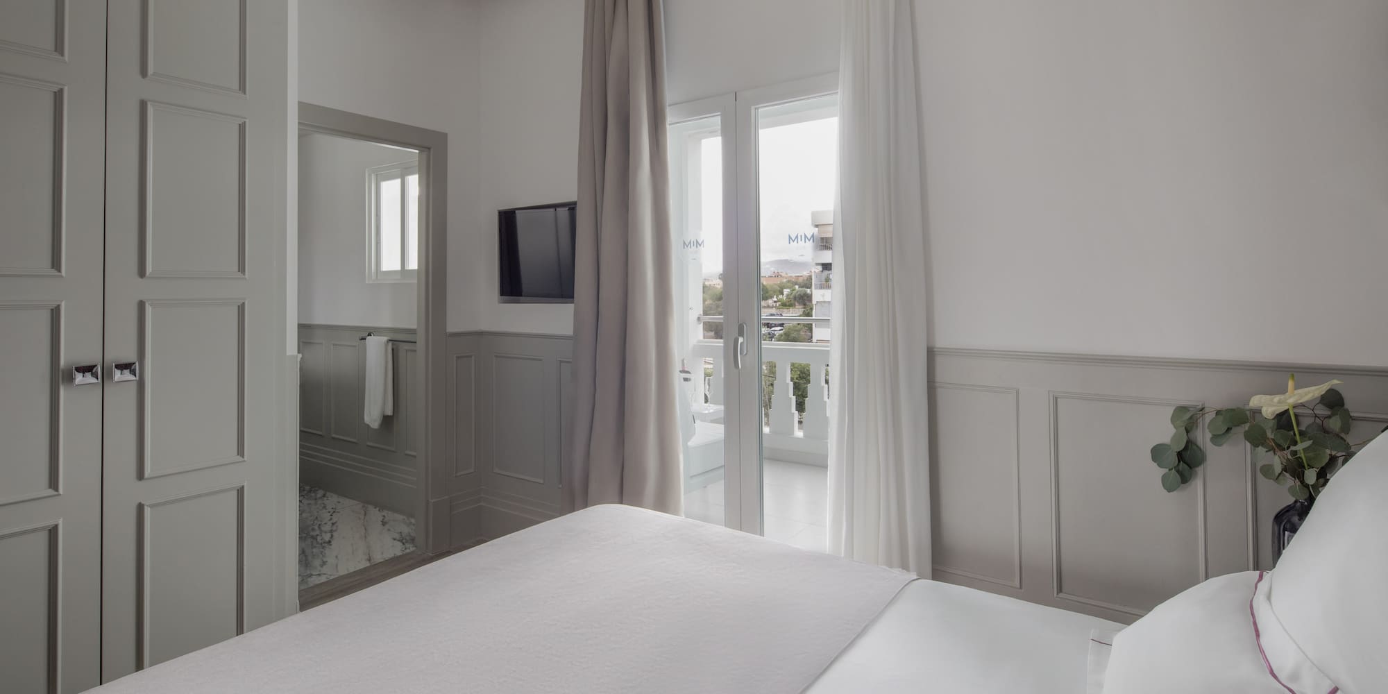 a bed in a room with a television and a balcony