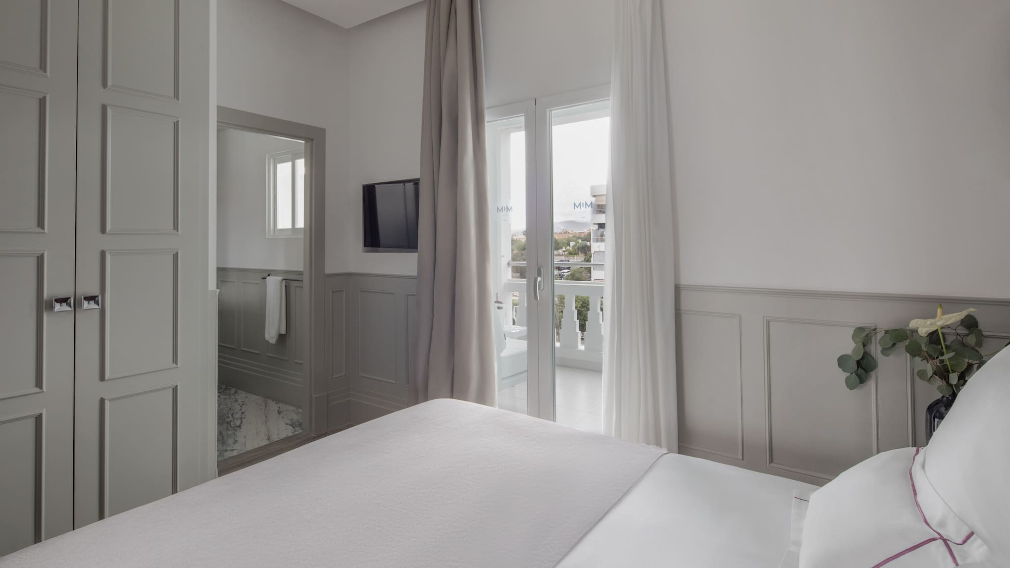 a bed in a room with a television and a balcony