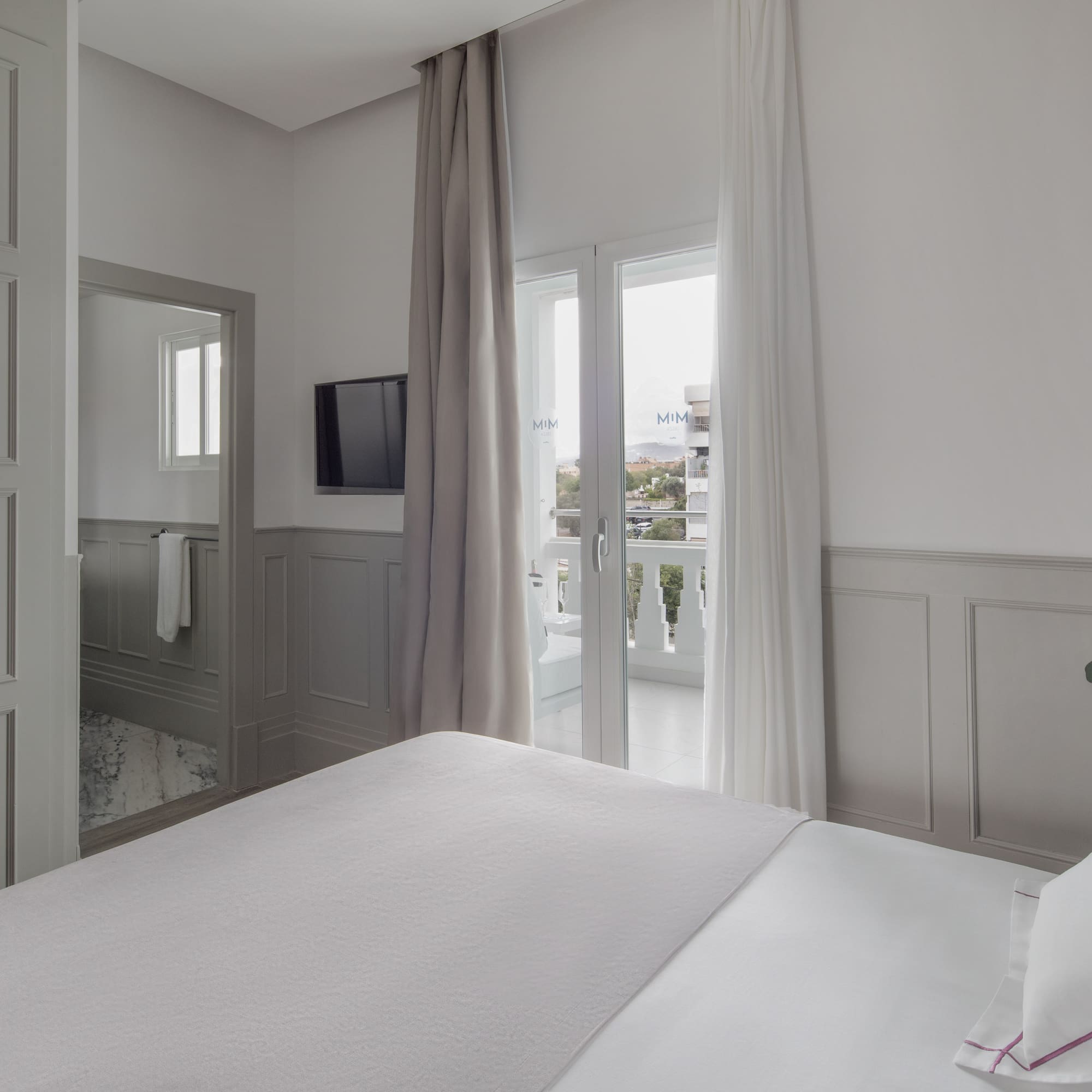 a bed in a room with a television and a balcony